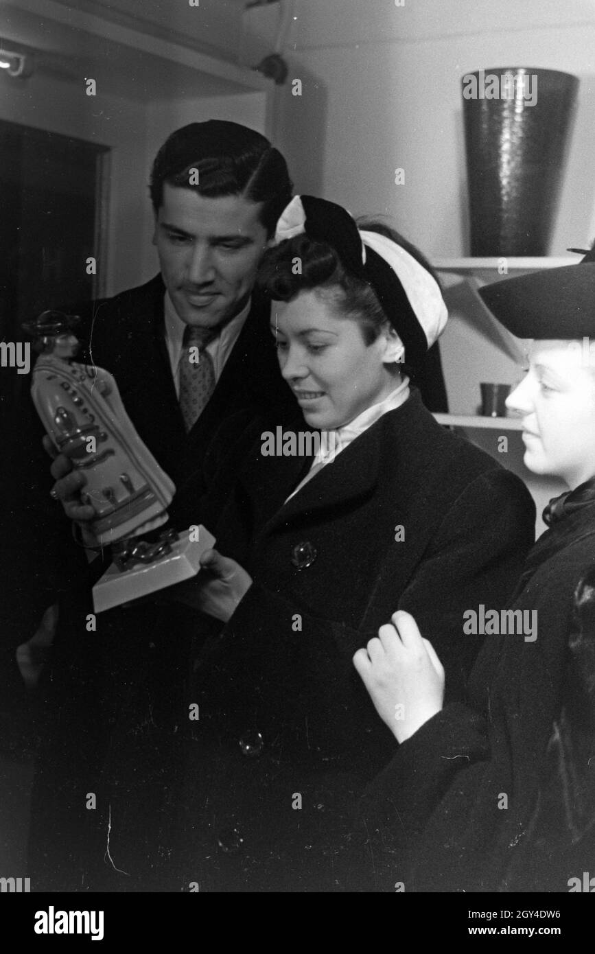 Besucher der Wiener Modewoche, im Haus der mode 'Palais Lobkowitz', betrachten ungarisches Kunsthandwerk; Deutschland 1940er Jahre.Visiteurs de la semaine de la mode de Vienne, dans la maison de la mode 'Palais Lobkowitz', regardant l'art et l'artisanat hongrois; Allemagne années 1940. Banque D'Images