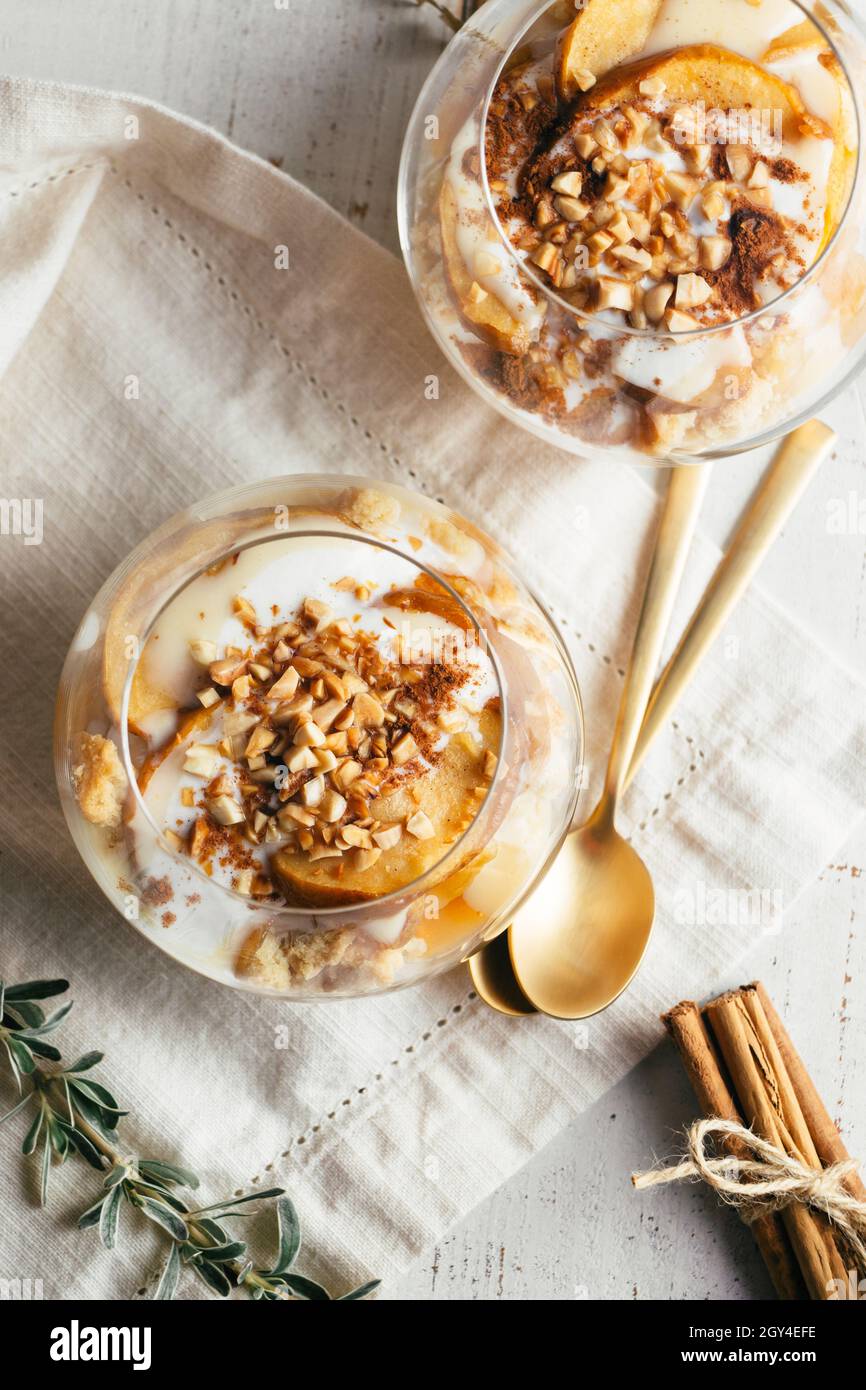 Dessert de Noël ou d'automne dans des verres à base de pommes au four, biscuits croquants aux amandes, crème anglaise, confiture, yaourt,cannelle et amandes grillées.Parait. T Banque D'Images