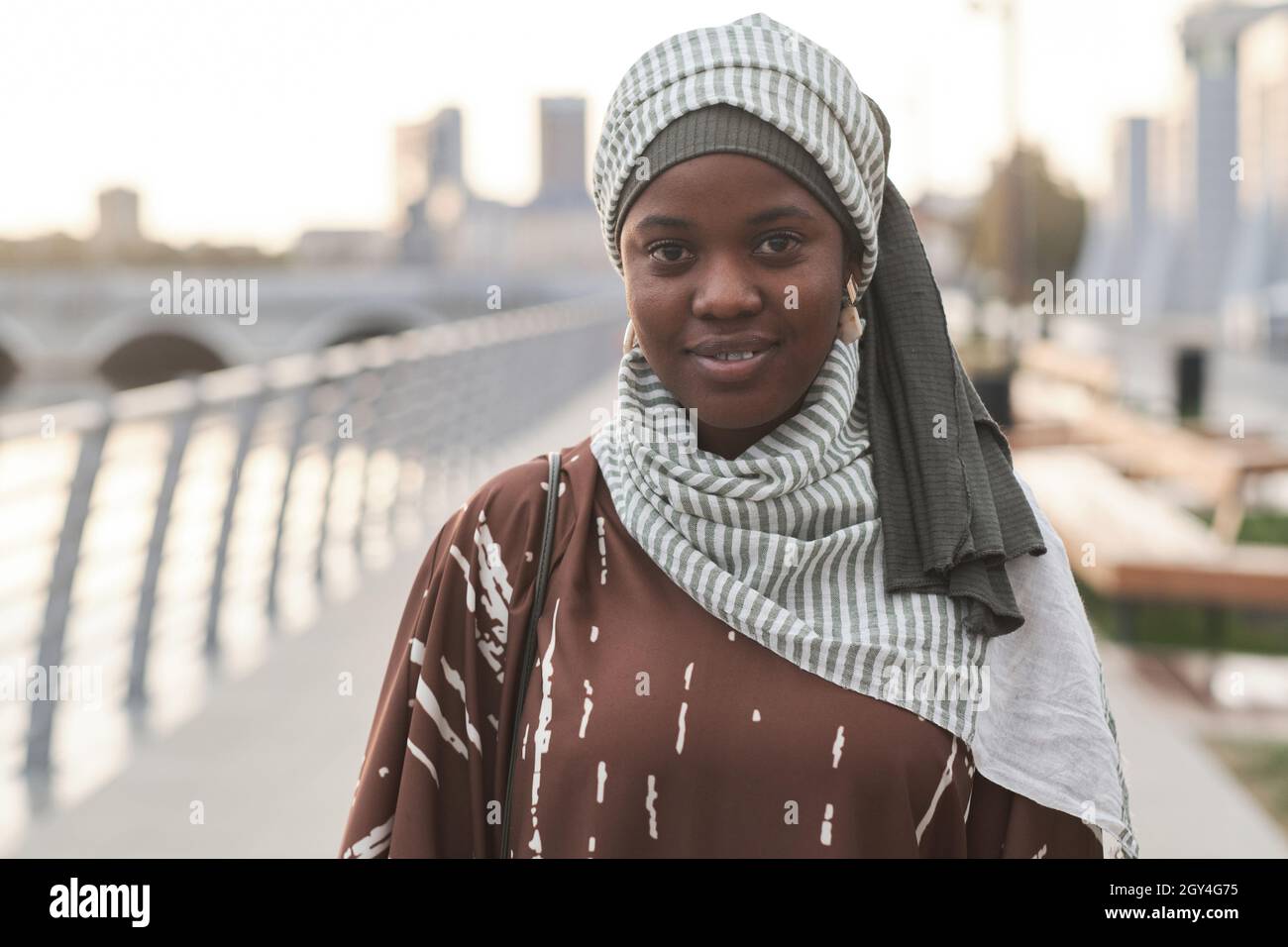 Portrait d'une jeune femme africaine vêtue de musulmans souriant à l'appareil photo tout en se tenant debout à l'extérieur Banque D'Images