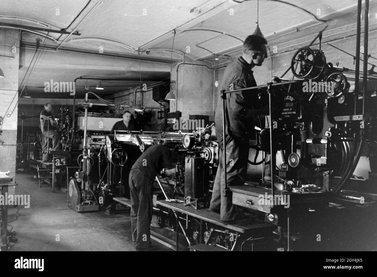 Druckereimitarbeiter bei der Arbeit an der Rotationsdruckmaschine Maschinenbaukonzerns in den Werken des MAN (Maschinenfabrik Augsburg-Nürnberg), Deutschland 1930 er Jahre. Les travailleurs de l'imprimerie sur la presse d'impression rotative dans les usines de la société d'ingénierie mécanique (homme), Maschinenfabrik Augsburg-Nürnberg Allemagne 1930. Banque D'Images