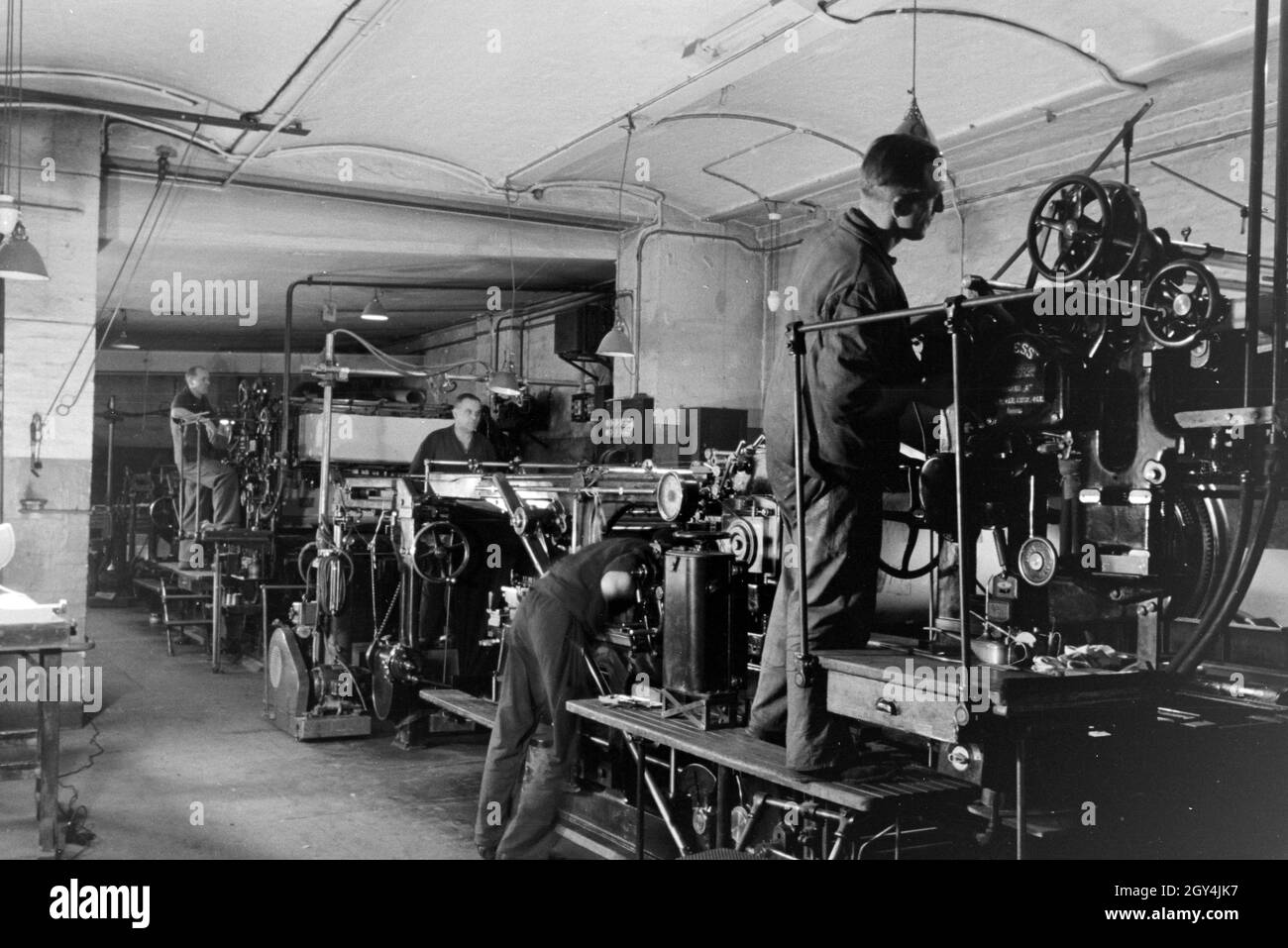 Druckereimitarbeiter bei der Arbeit an der Rotationsdruckmaschine Maschinenbaukonzerns in den Werken des MAN (Maschinenfabrik Augsburg-Nürnberg), Deutschland 1930 er Jahre. Les travailleurs de l'imprimerie sur la presse d'impression rotative dans les usines de la société d'ingénierie mécanique (homme), Maschinenfabrik Augsburg-Nürnberg Allemagne 1930. Banque D'Images