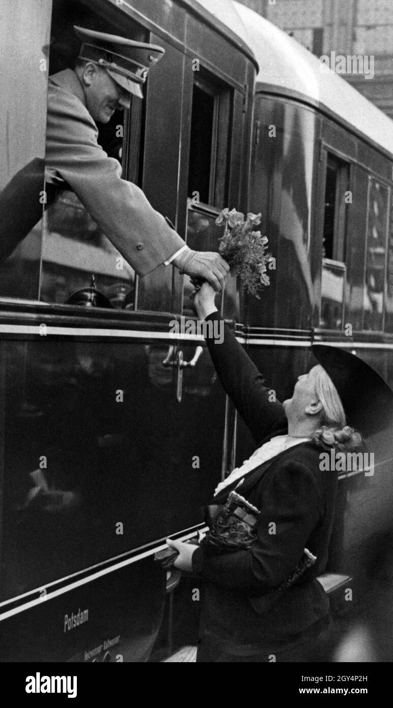 Avant son départ de la gare Anhalter Bahnhof de Berlin, Adolf Hitler est présenté avec un bouquet de fleurs par un admirateur.[traduction automatique] Banque D'Images