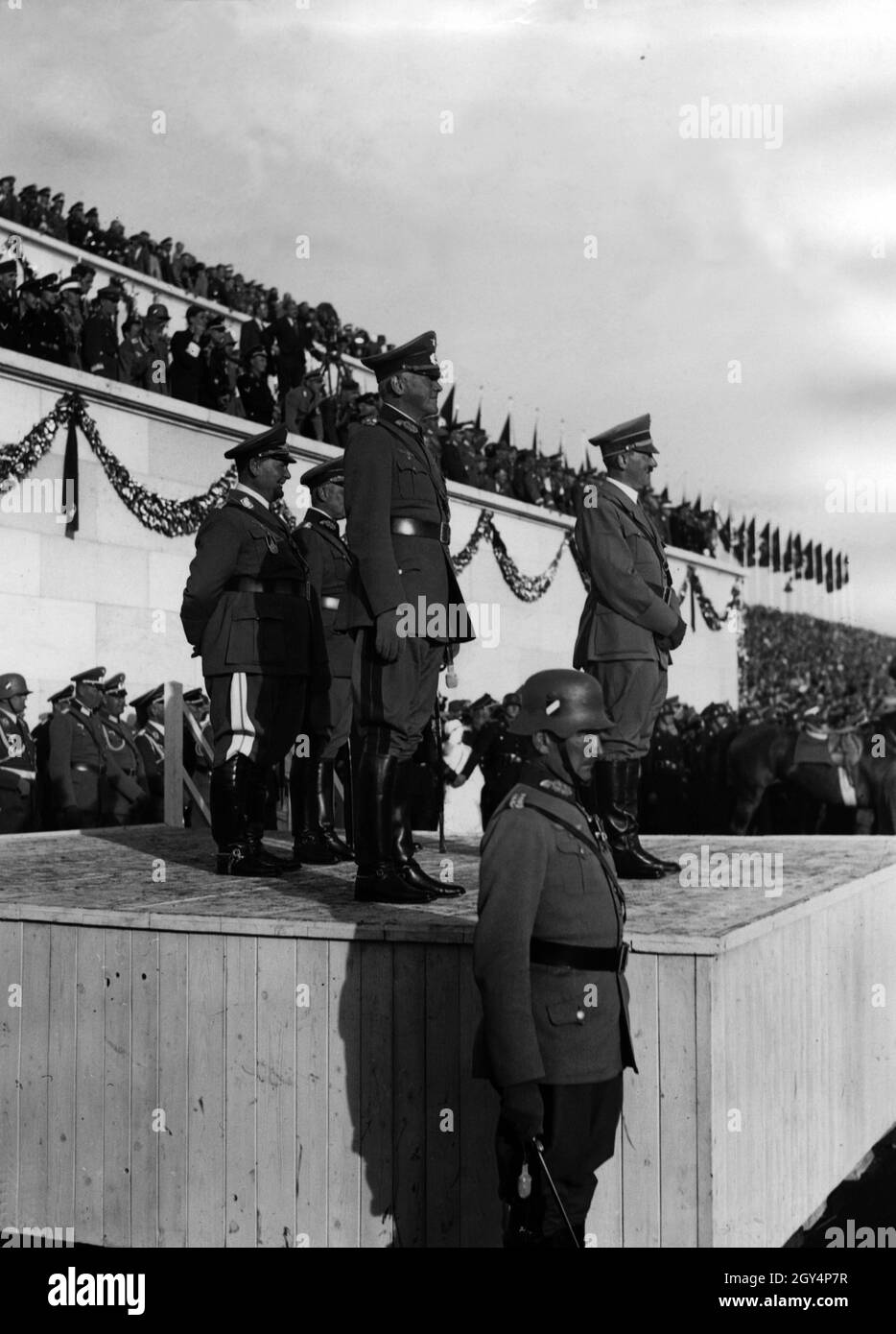 Adolf Hitler prend un défilé de la Wehrmacht le jour de la Wehrmacht pendant le Congrès du Parti Reich de la liberté en 1935.À côté d'Hitler, le maréchal Werner von Blomberg observe les troupes qui passent, le commandant en chef de la Force aérienne Hermann Göring et le commandant en chef de l'armée Werner von Fritsch se tenant dans la deuxième rangée.[traduction automatique] Banque D'Images