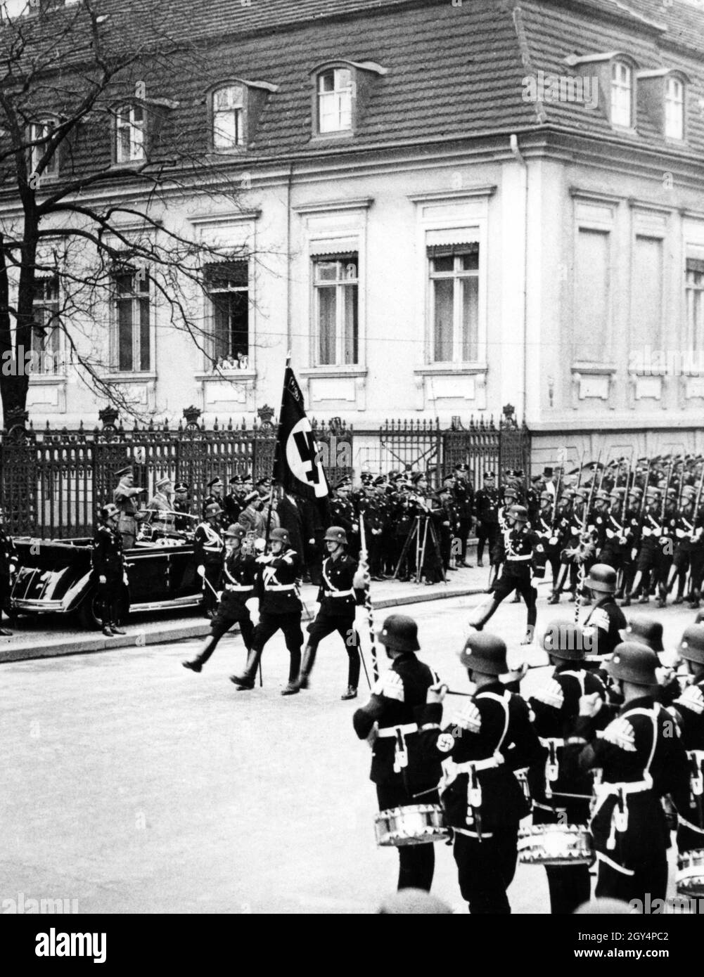 Adolf Hitler debout dans une Mercedes convertible W 150, devant laquelle Heinrich Himmler (à gauche) et le commandant de la SS Leibstandarte Adolf Hitler et Obergruppenführer Sepp Dietrich sont également debout, salue les unités SS de la Leibstandarte qui ont passé avec le salut d'Hitler.[traduction automatique] Banque D'Images