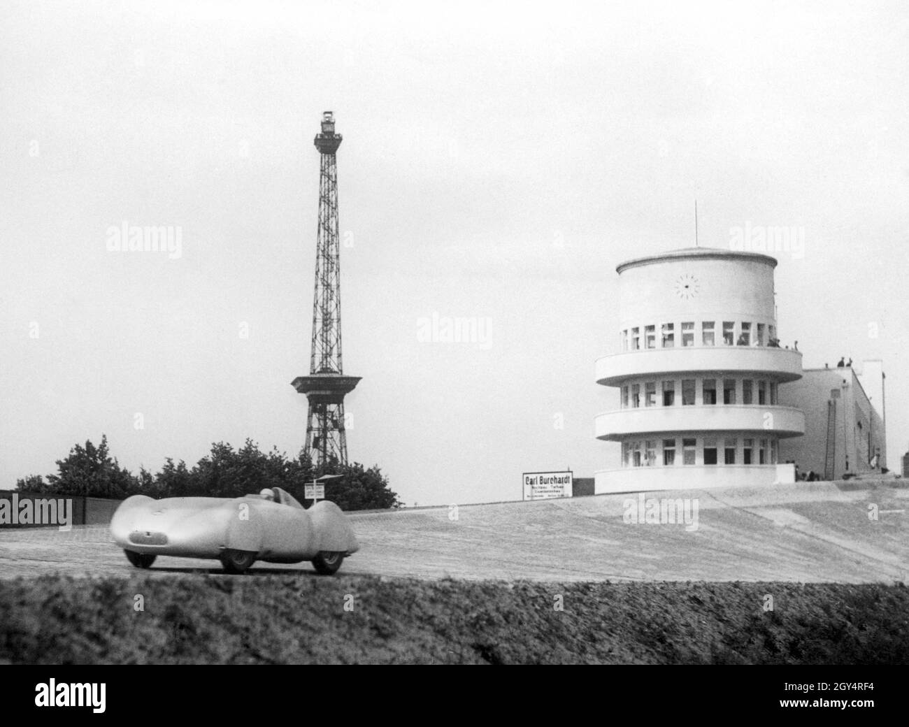 Rudolf Caracciola a parcouru des tours d'entraînement sur l'Avus à Berlin le 02 mai 1937, alors la piste de course la plus rapide au monde.Ici, il conduit sa flèche d'argent sur la droite après avoir quitté la courbe nord convertie.En arrière-plan se trouvent la tour de radio de Berlin et un nouveau bâtiment administratif avec une tour de juge d'arrivée sur la piste de course.[traduction automatique] Banque D'Images