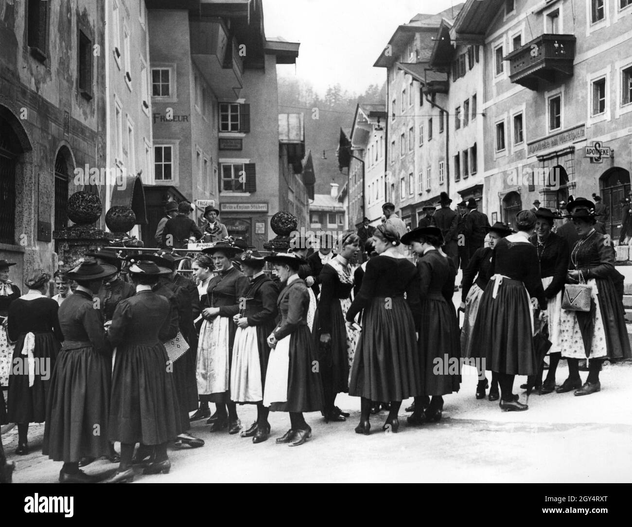 «après le service de l'église le dimanche matin, le 10 mai 1937, les femmes se rencontrent sur le marché de Berchtesgaden en face de la Hirschenhaus pour parler.Sur la droite dans la maison n°8 est la pharmacie sur la place du marché, sur la gauche dans les maisons n°7 et 9 il y a un coiffeur et la charcuterie ''Wein und Enzian-Stüberl''.[traduction automatique]' Banque D'Images