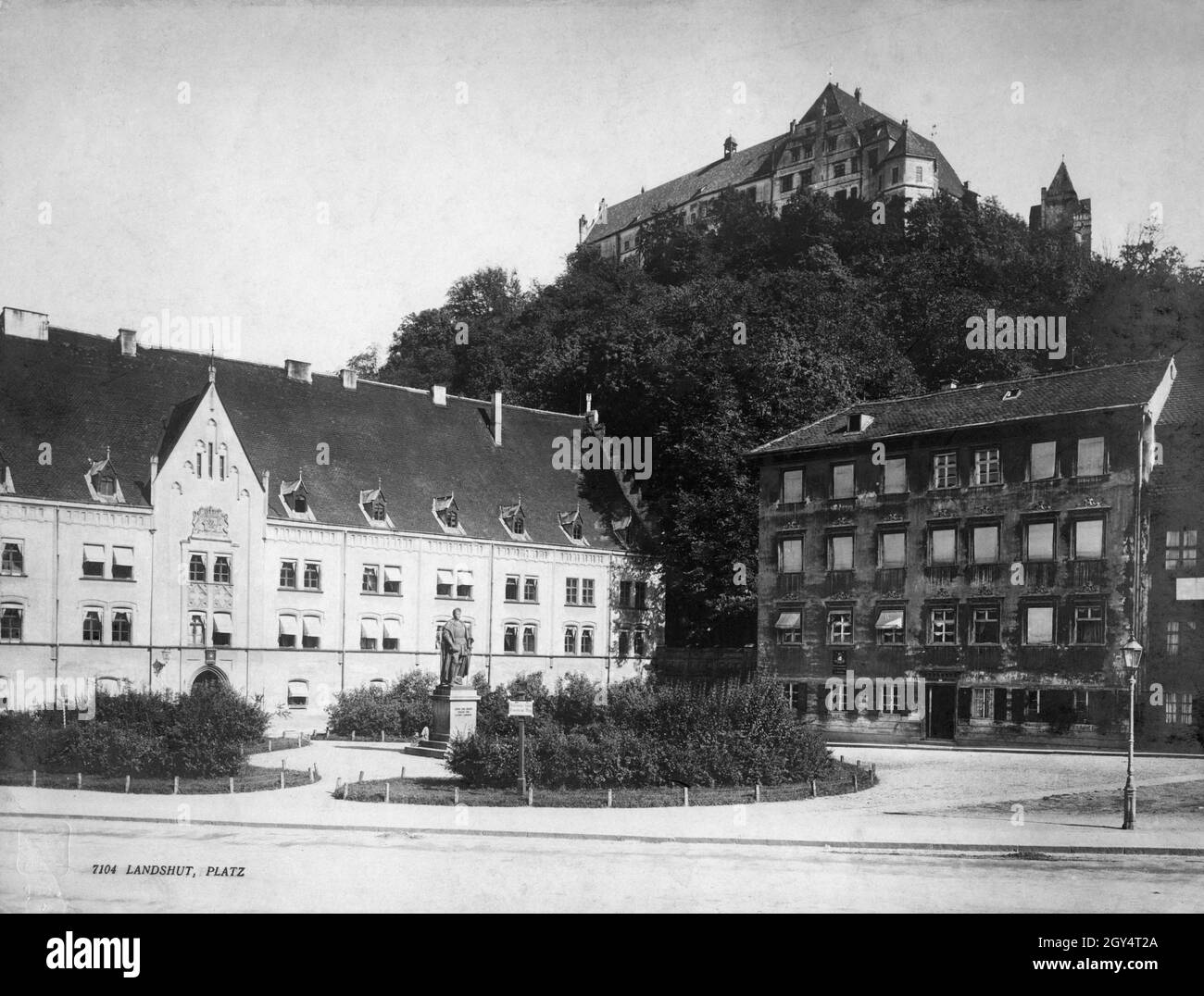 'Sur Dreifaltigkeitsplatz, vu ici en 1904, est un monument au Duc Ludwig le riche avec l'inscription ''Ludwig der Reiche / Herzog von / Bayern Landshut'.La place est bordée par l'ancienne cour ducale (puis la Cour royale du comté, à gauche) et le bâtiment Dreifaltigkeitsplatz n° 176, dont la façade est assez délabrée.Sur la pelouse (au centre de l'image) se trouve un panneau avec l'inscription : ''Nach dem kgl.Schloße / Trausnitz und Berg'.Au-dessus de la place de la Hofberg se trouve le château de Trausnitz.[traduction automatique]' Banque D'Images