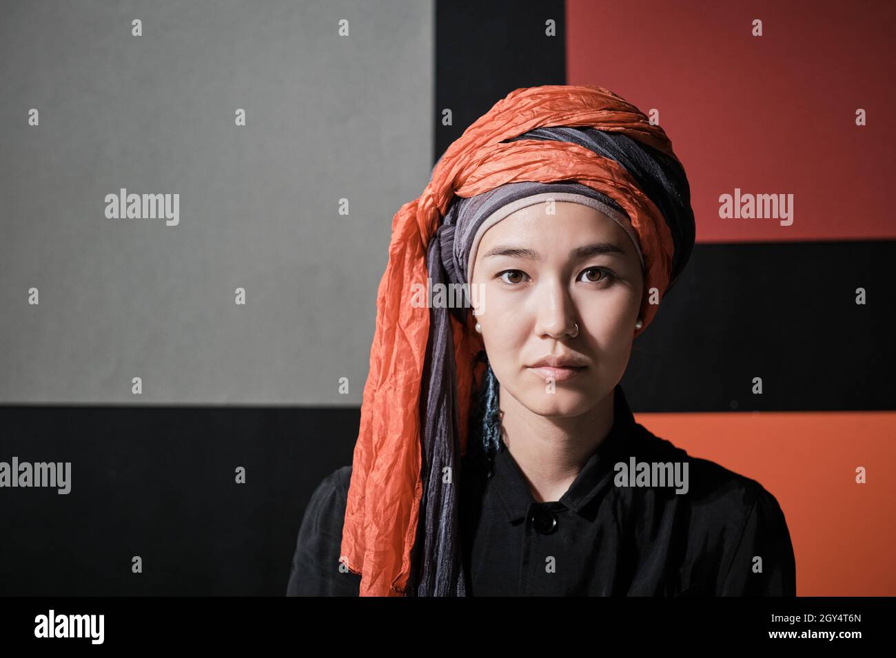Portrait d'une jeune belle femme en vêtements musulmans regardant l'appareil photo contre le mur coloré Banque D'Images
