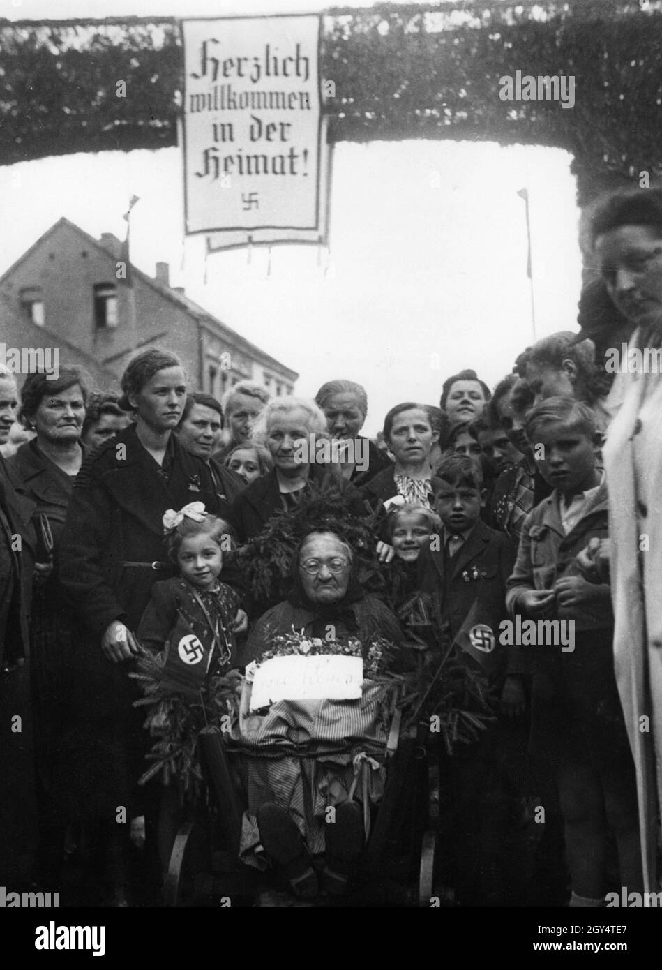 'Alsatians et Lorraine résident de retour dans la région occupée par les Allemands.Sur la photo : un groupe de personnes entoure une vieille femme en fauteuil roulant dans sa ville natale.Ils sont debout devant une arcade sur laquelle une affiche lit ''Bienvenue à la maison![traduction automatique]' Banque D'Images