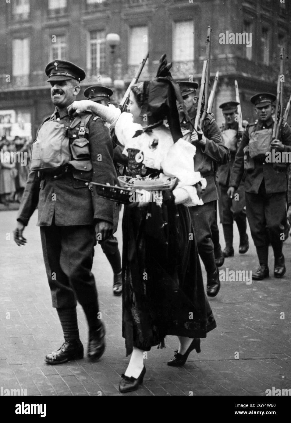 Arrivée des soldats britanniques à Paris : une jeune française en costume alsacien met des fleurs sur le revers d'un soldat comme signe d'amitié franco-britannique.[traduction automatique] Banque D'Images