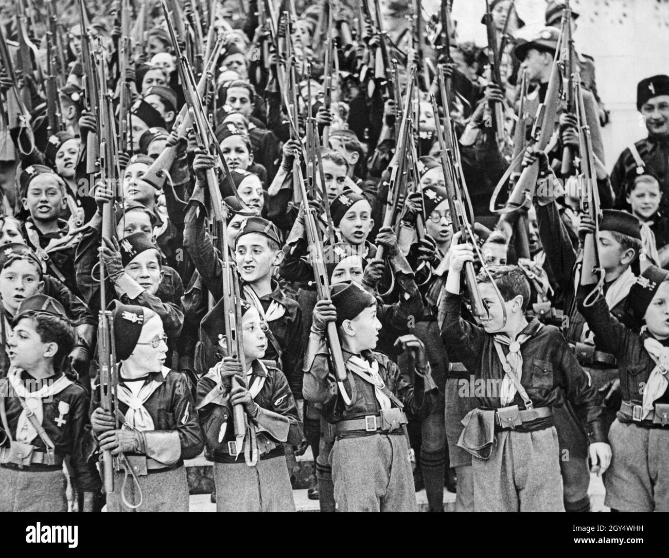 Pour célébrer le jour de l'armistice, de grands défilés ont eu lieu en Italie en 1935.De nombreuses unités de l'organisation de jeunesse fasciste Opera Nazionale Balilla y ont participé.Sur la photo, un détachement de garçons Balilla se tient sur une tribune et les acclamations avec leurs fusils sont élevées.[traduction automatique] Banque D'Images