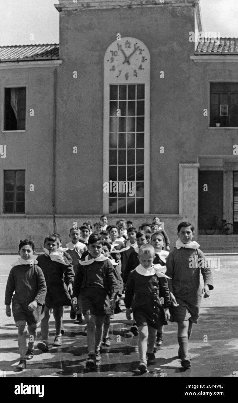 Un cours d'école italienne traverse le terrain de jeu de l'école en 1938.Tous les garçons portent des uniformes scolaires de sorte qu'aucune distinction de classe n'est apparente.[traduction automatique] Banque D'Images