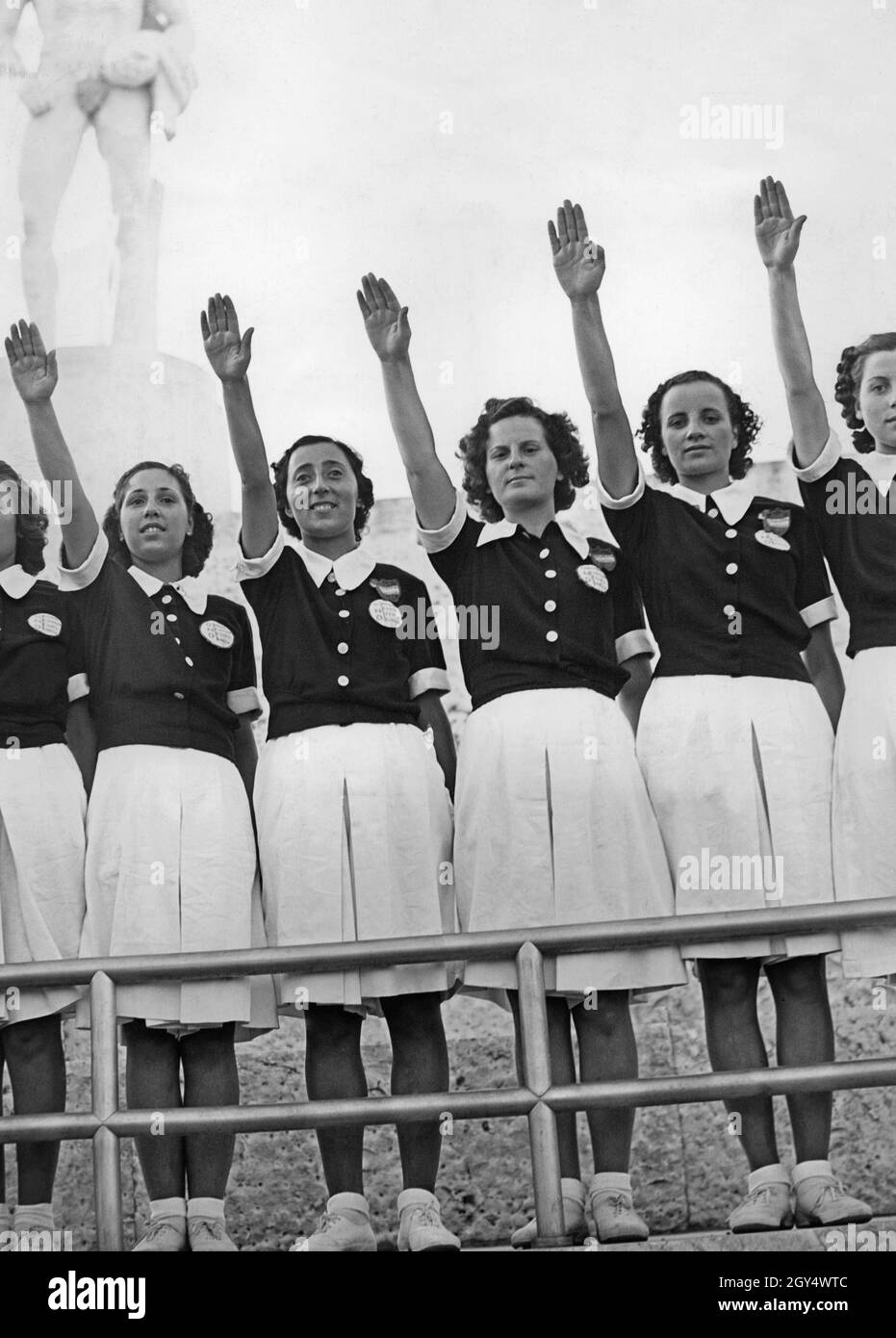 «les filles et les jeunes femmes, âgées de 16 à 20 ans, qui ont grandi avec le fascisme, lèvent leurs bras dans le salut romain.Ils sont dans le stade en marbre du Foro Mussolini (aujourd'hui Foro Italico) et appartiennent au fasciste ''Opera nazionale del dopolavoro' (OND).La photographie a été prise en 1938.[traduction automatique]' Banque D'Images