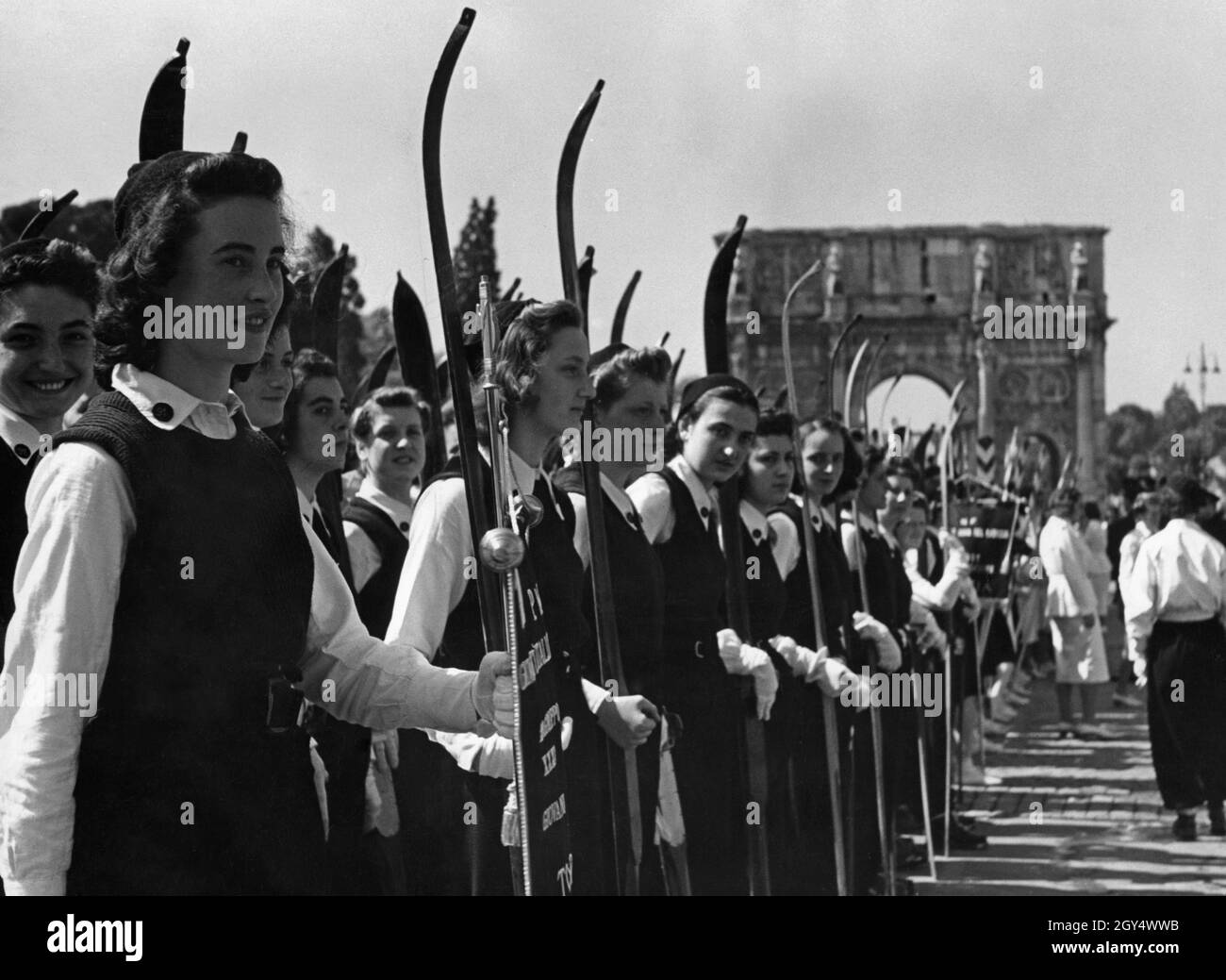 Les filles appartenant à la Giovani Italiane au sein de l'organisation fasciste de jeunesse Gioventu Italiana del Littorio (GIL) se tiennent dans leur section sur la via Trionfale (maintenant via di San Gregorio) à Rome.Ils participent à une parade des jeunes fascistes en 1939.Le groupe de filles est la section de ski du GIL de Turin.L'Arc de Constantine peut être vu en arrière-plan.[traduction automatique] Banque D'Images