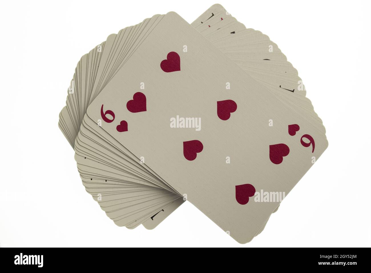 Jeu de cartes incurvé.Un six rouge figure ci-dessus.Photographié sur un fond blanc et propre, avec un gros plan Banque D'Images
