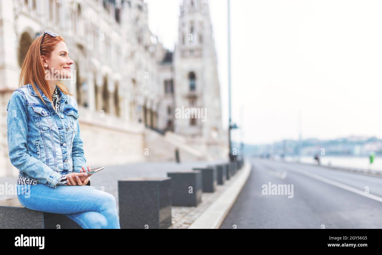 Jeune femme hongroise à tête rouge, assise sur pierre au Parlement de Budapest, Hongrie, en vue Banque D'Images