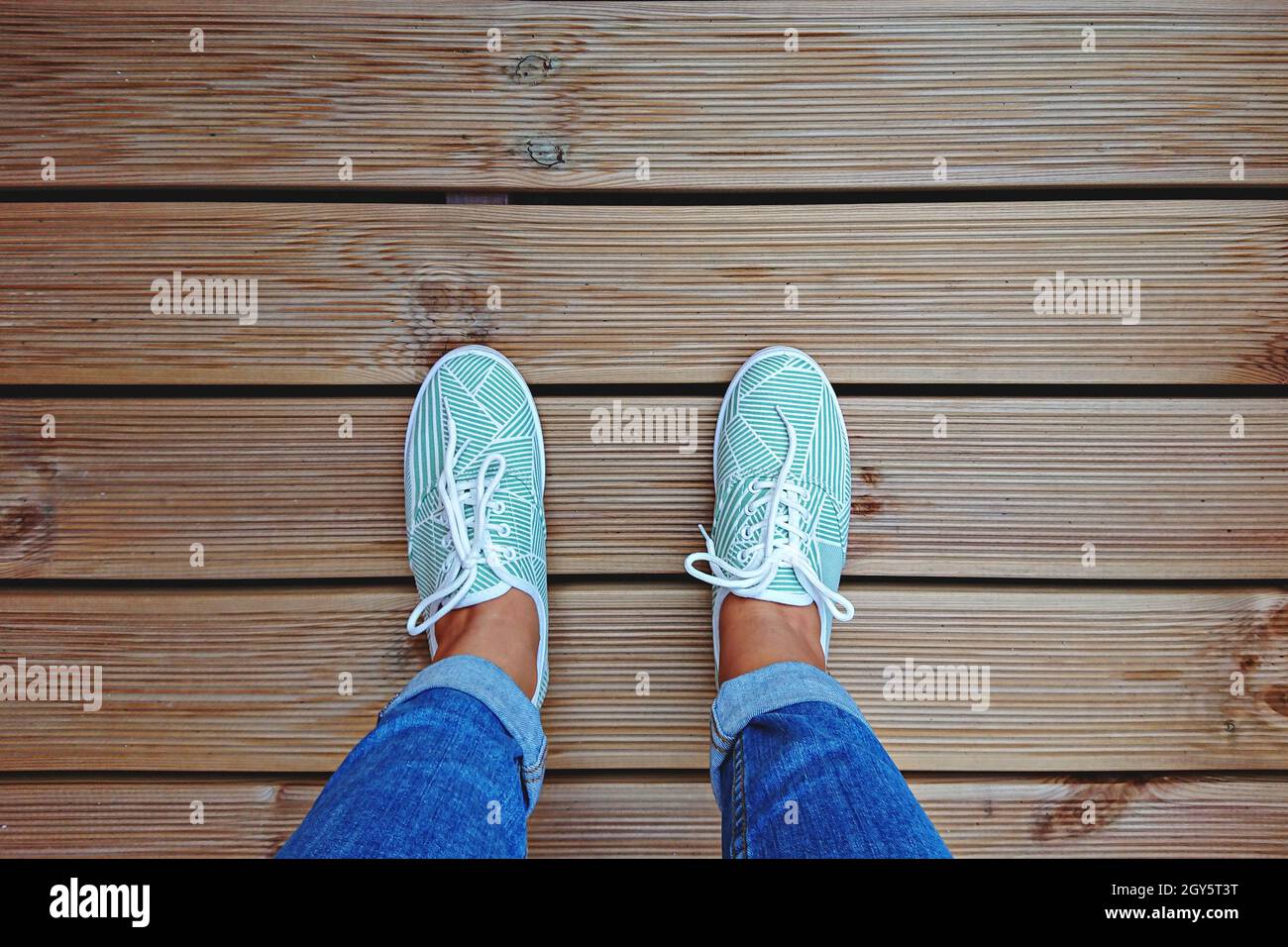 Jambes pour Femme en Sneakers vertes menthe sur la terrasse avec espace de copie. Vue de dessus et point de vue personnel Banque D'Images