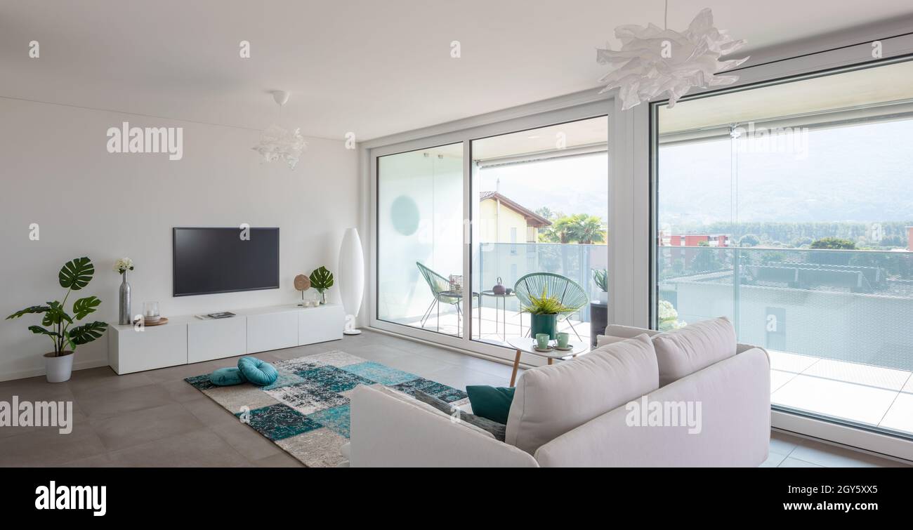 Salon moderne avec mobilier de créateur.Canapé avec coussins clairs et vue sur le balcon.Personne à l'intérieur.Vue frontale, panorama Banque D'Images