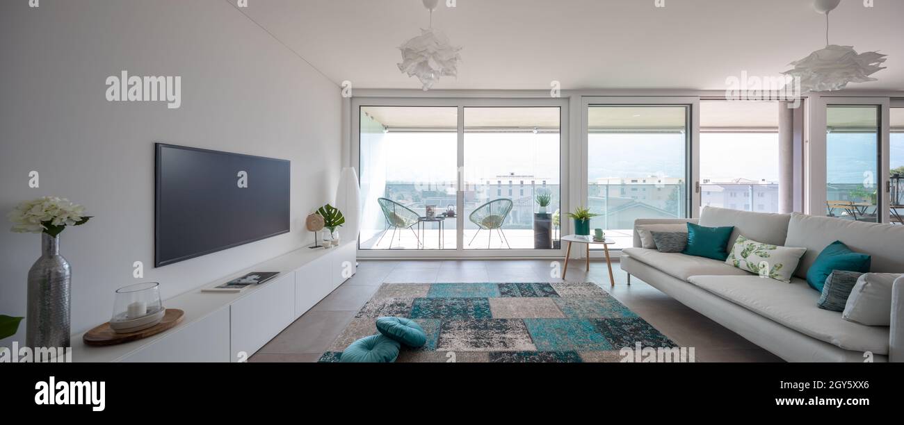 Salon moderne avec mobilier de créateur.Canapé avec coussins clairs et vue sur le balcon.Personne à l'intérieur.Vue frontale, panorama Banque D'Images
