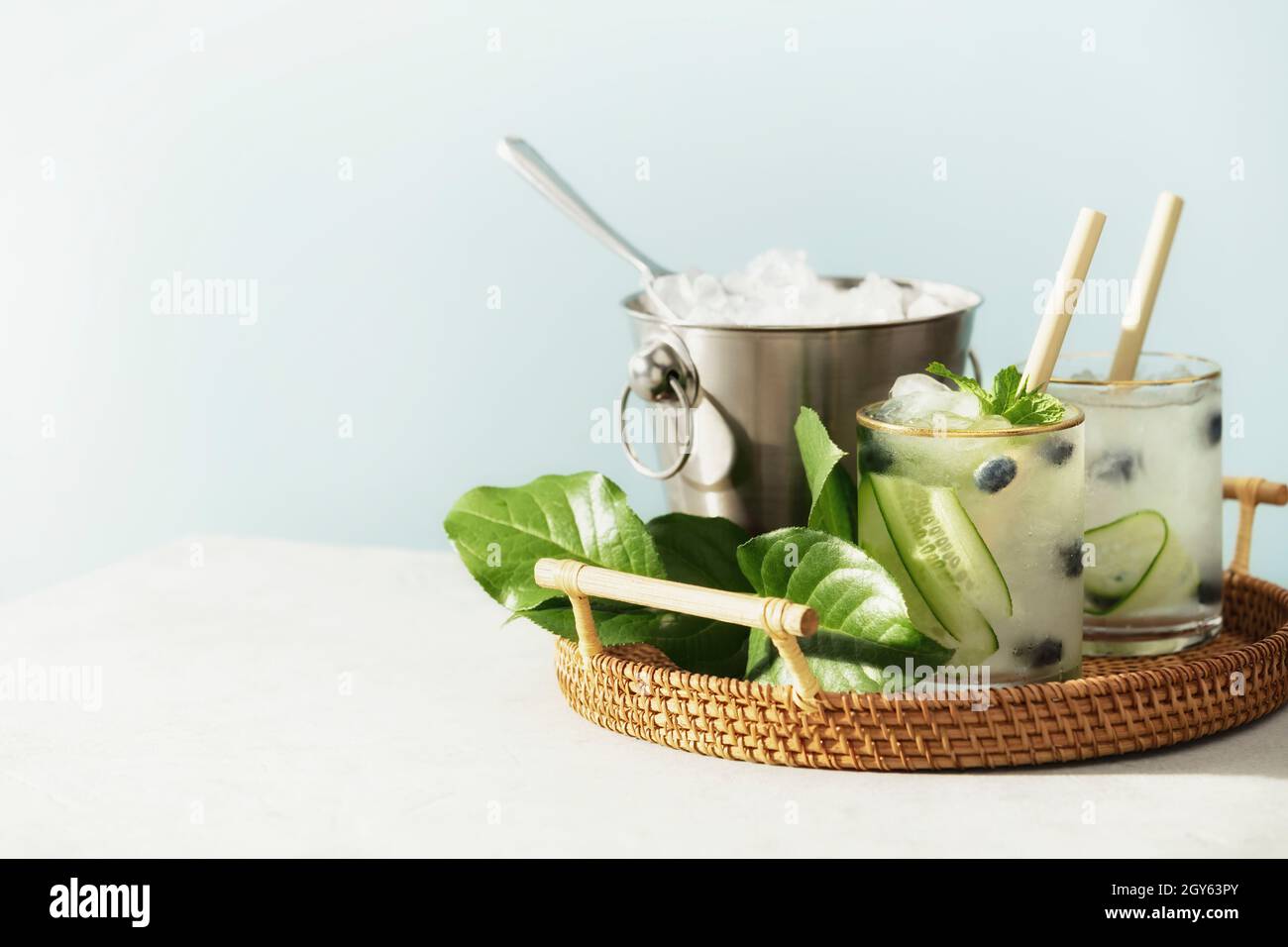 Boissons d'été tendance avec concombre, menthe et myrtille sur fond bleu ciel Banque D'Images