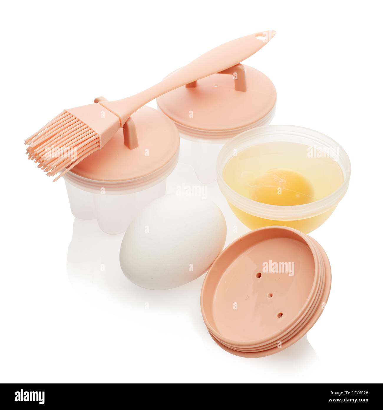 Ensemble de moules en silicone résistant à la chaleur pour les œufs pochés,  la brosse à badigeonner et les œufs frais crus isolés sur fond blanc. Ustensile de cuisson.Œuf poché Photo Stock -