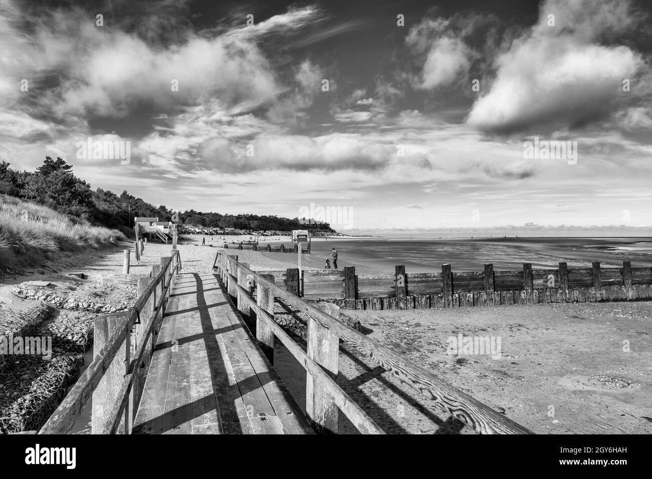 Promenade menant à des cabanes de plage et de plage donnant sur la baie de Holkham à Well-Next-the-Sea sur un matin lumineux et ensoleillé d'octobre en Monochrome Banque D'Images
