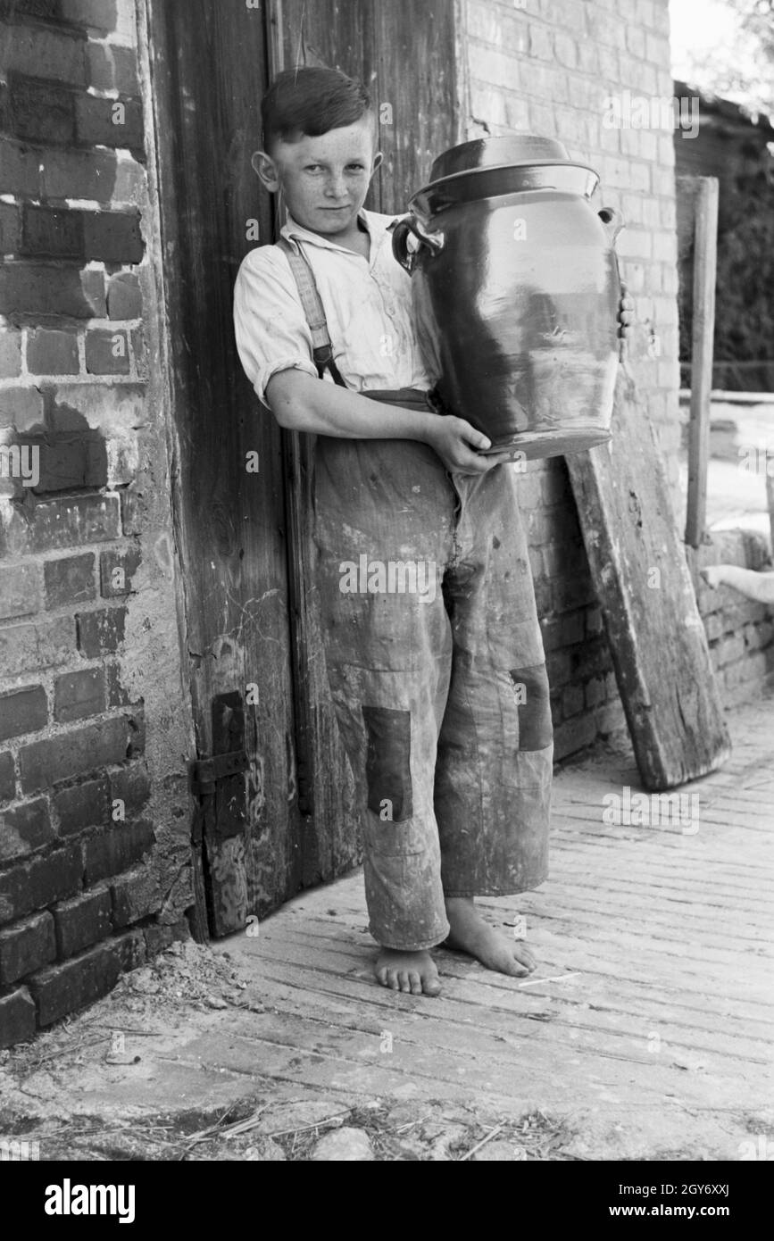 Ein Junge mit gebrannten Tontöpfen auf dem Hof eines Töpferei im Dorf Görzke dans le Brandebourg, Deutschland 1930 er Jahre. Un garçon avec des pots fini à la cour d'une poterie au village de Goerke à Brandebourg, Allemagne 1930. Banque D'Images