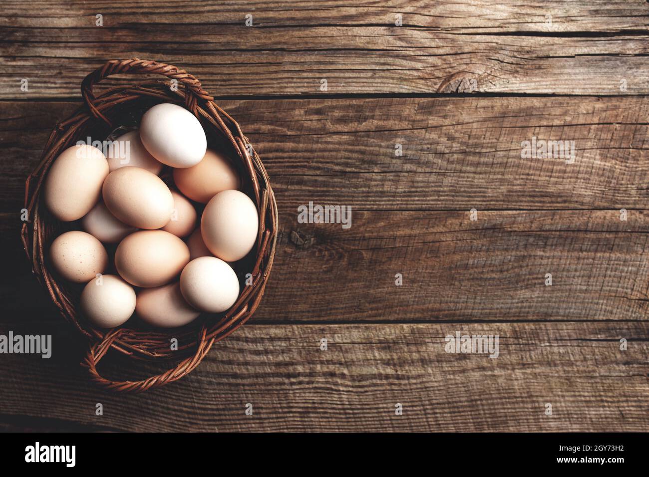 Pondre plat avec panier rempli d'œufs de poulet bio sur fond de bois. Concept de ménage biologique avec des œufs de poules élevées en liberté et en pâturage Banque D'Images