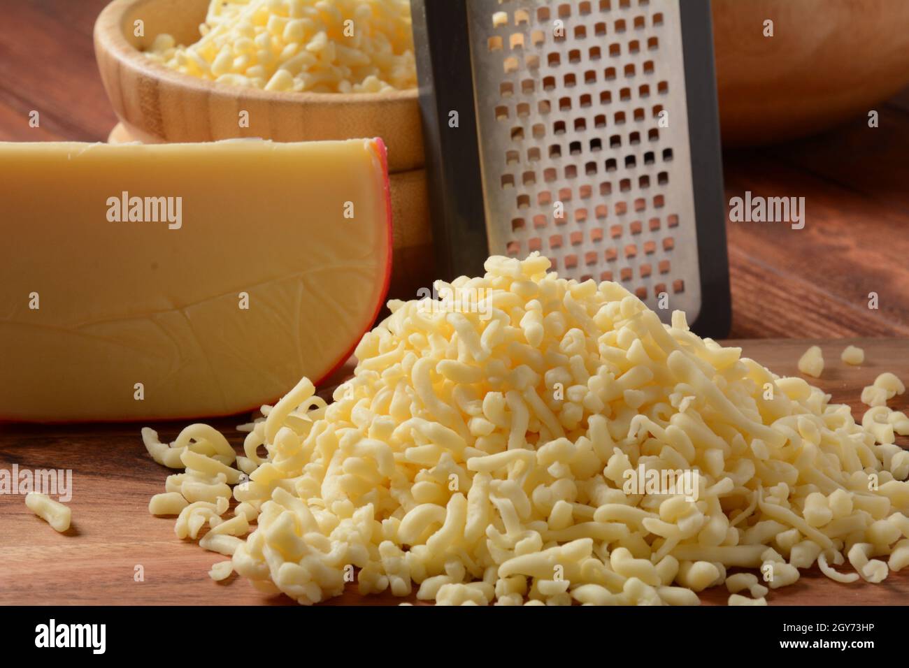 Tas de fromage râpé sur petit panneau en bois. Fromage râpé pour la cuisson sur une planche à découper sur fond de bois Banque D'Images