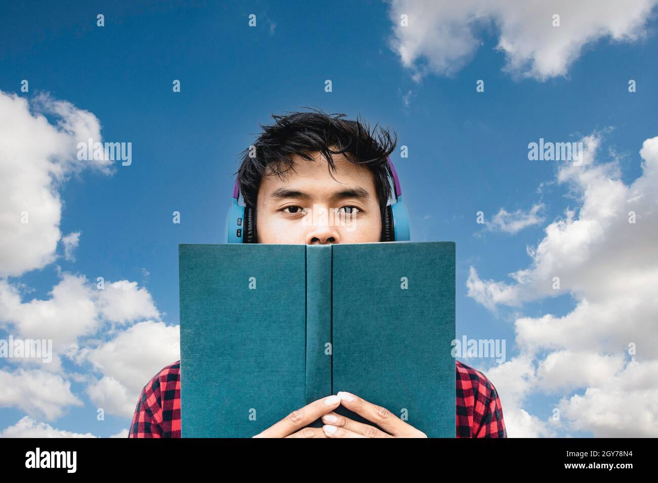 Jeunes asiatiques lisant un livre ou écoutant un livre audio contre un ciel bleu et des nuages - influenceur social asiatique s'amusant avec les nouvelles tendances de la technologie oppo Banque D'Images