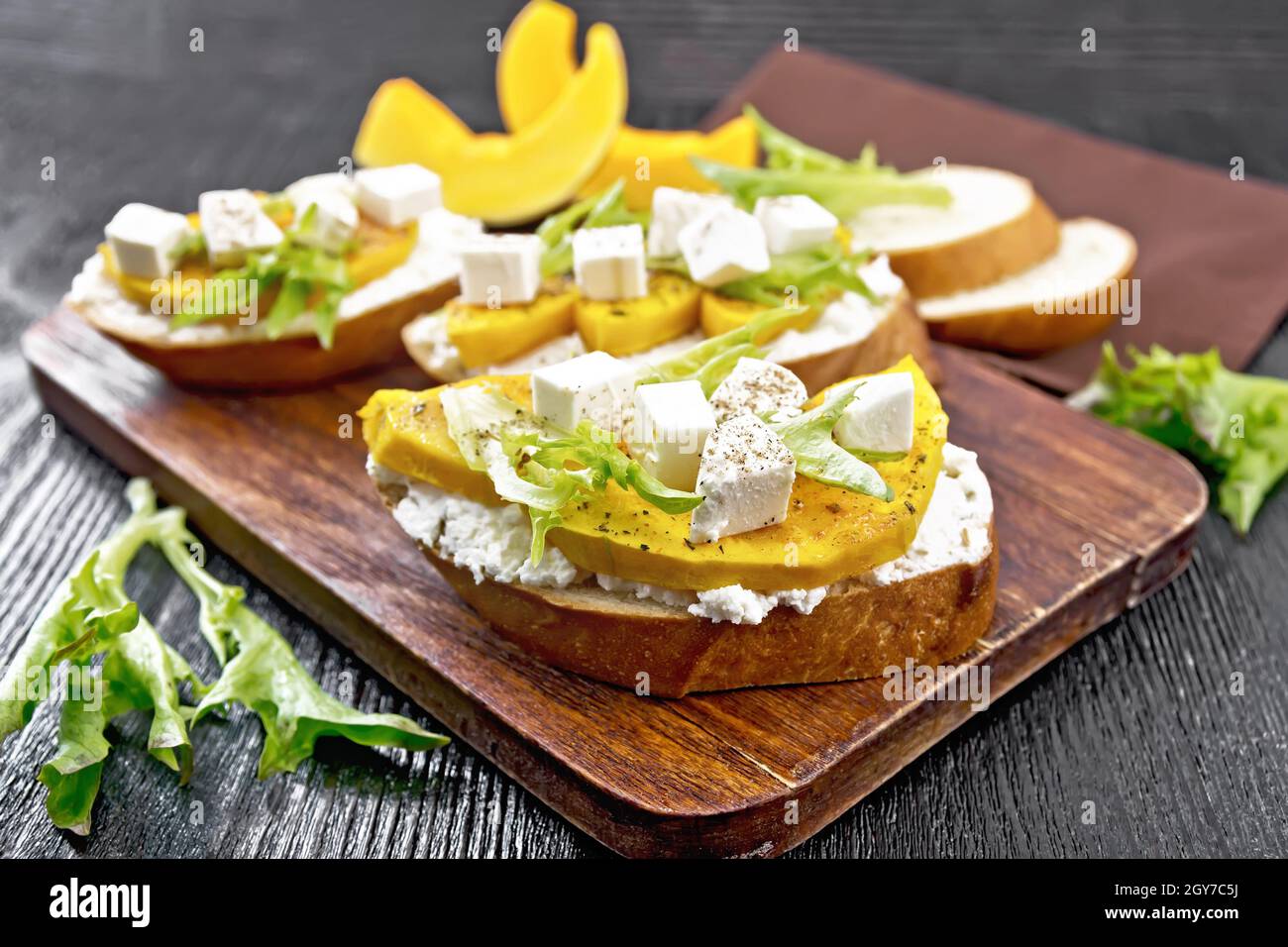 Bruschetta à la citrouille cuite au four, fromage féta salé, ricotta, arugula et épices, serviette et tranches de légumes sur fond de bois Banque D'Images