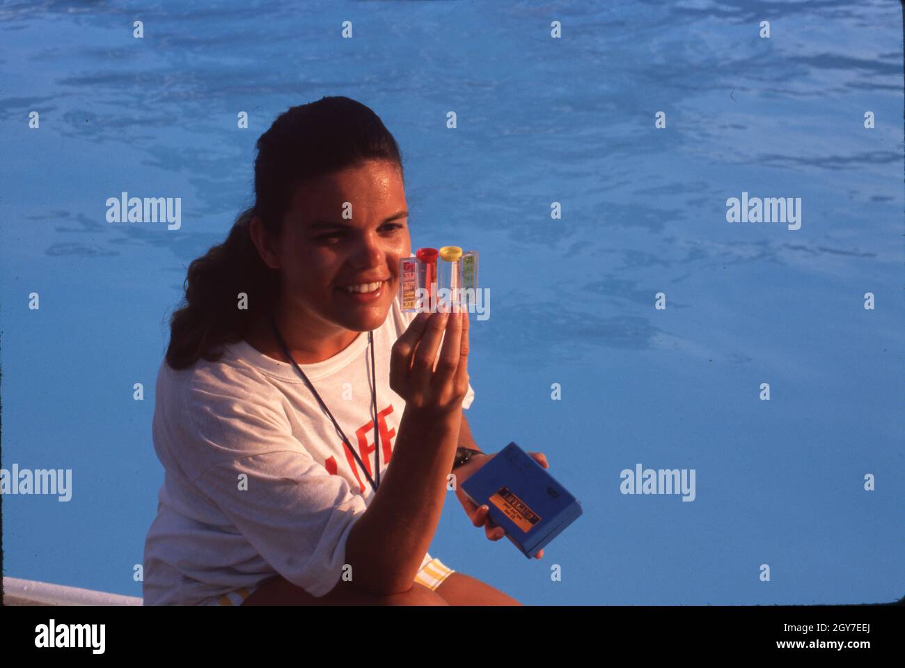 Austin Texas États-Unis, vers 1990 : le maître-nageur féminin adolescent vérifie le niveau de chlore de la piscine.©Bob Daemmrich Banque D'Images