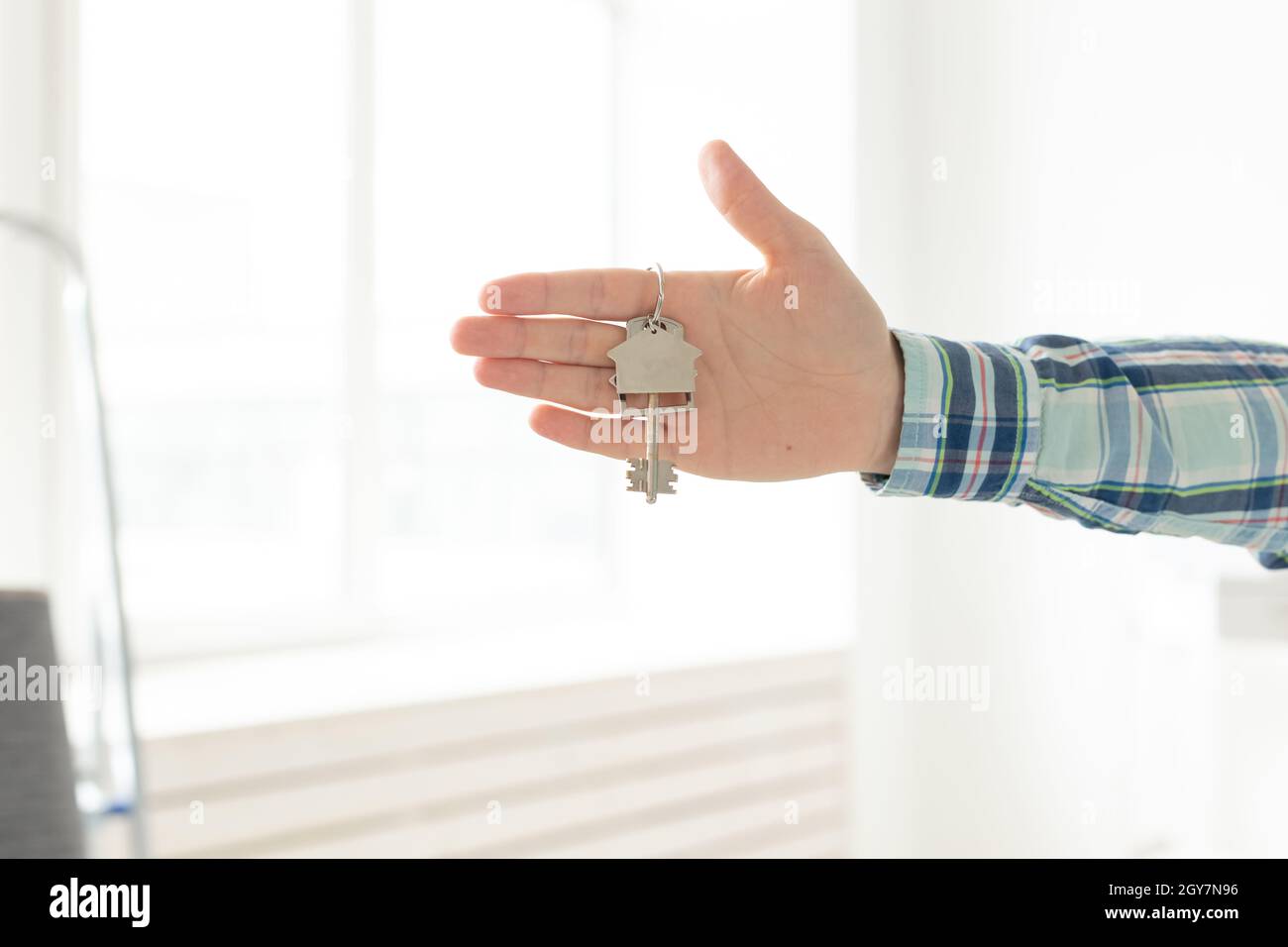 Tenir les clés de la maison sur le porte-clés en forme de maison dans une nouvelle maison.Concept de prêt hypothécaire et de prêt immobilier Banque D'Images