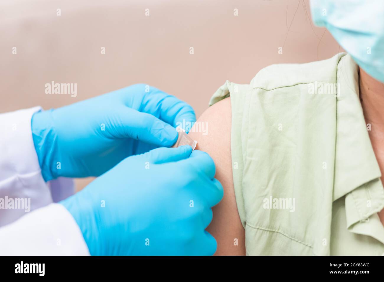 Vaccination, Docteur homme après injection coronavirus vaccin à la jeune femme épaule il caoutchouc gants de protection mettre un pansement adhésif, C Banque D'Images