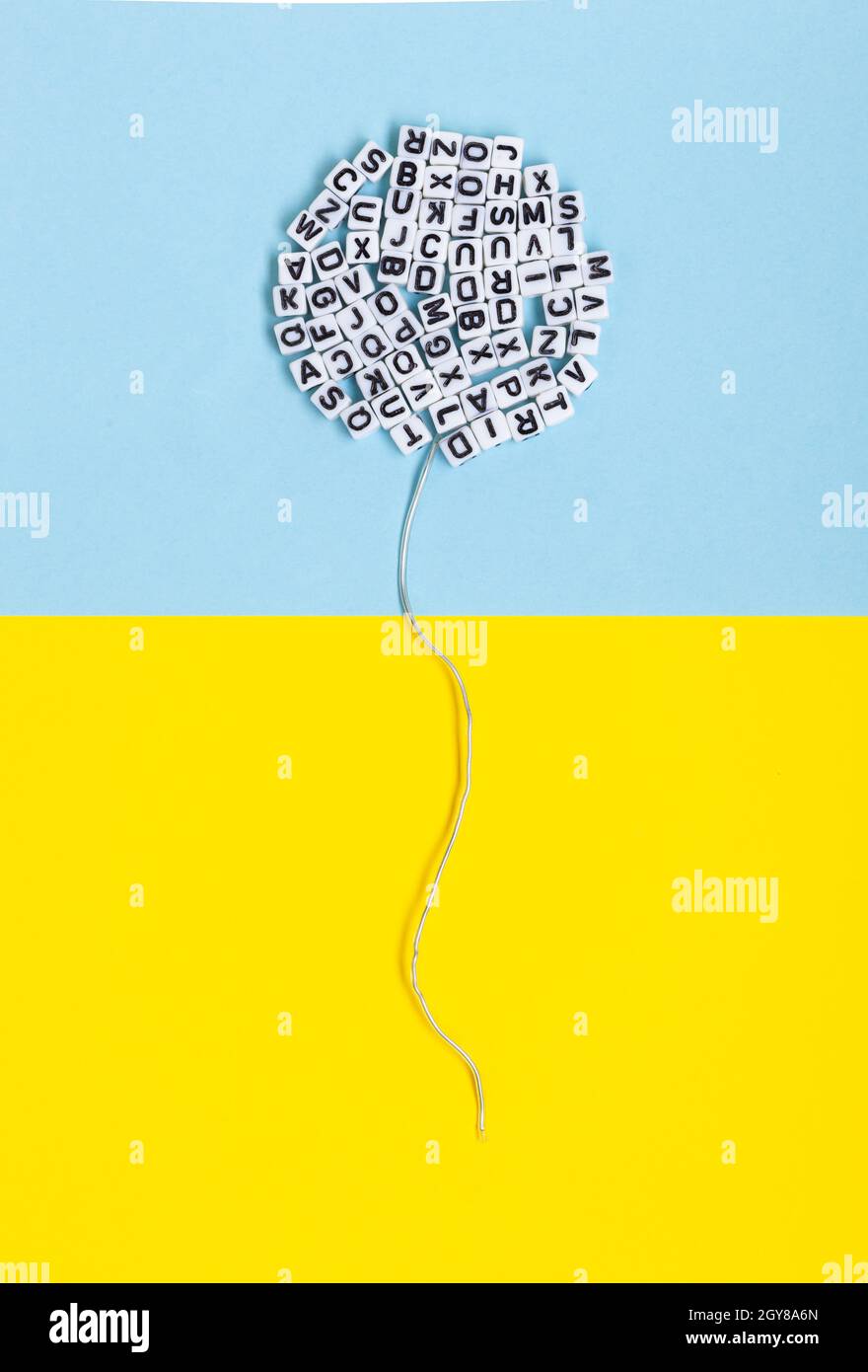 Bulle composée de lettres sur fond jaune et bleu. Image conceptuelle de la littérature, de la langue et de la liberté d'expression. Banque D'Images