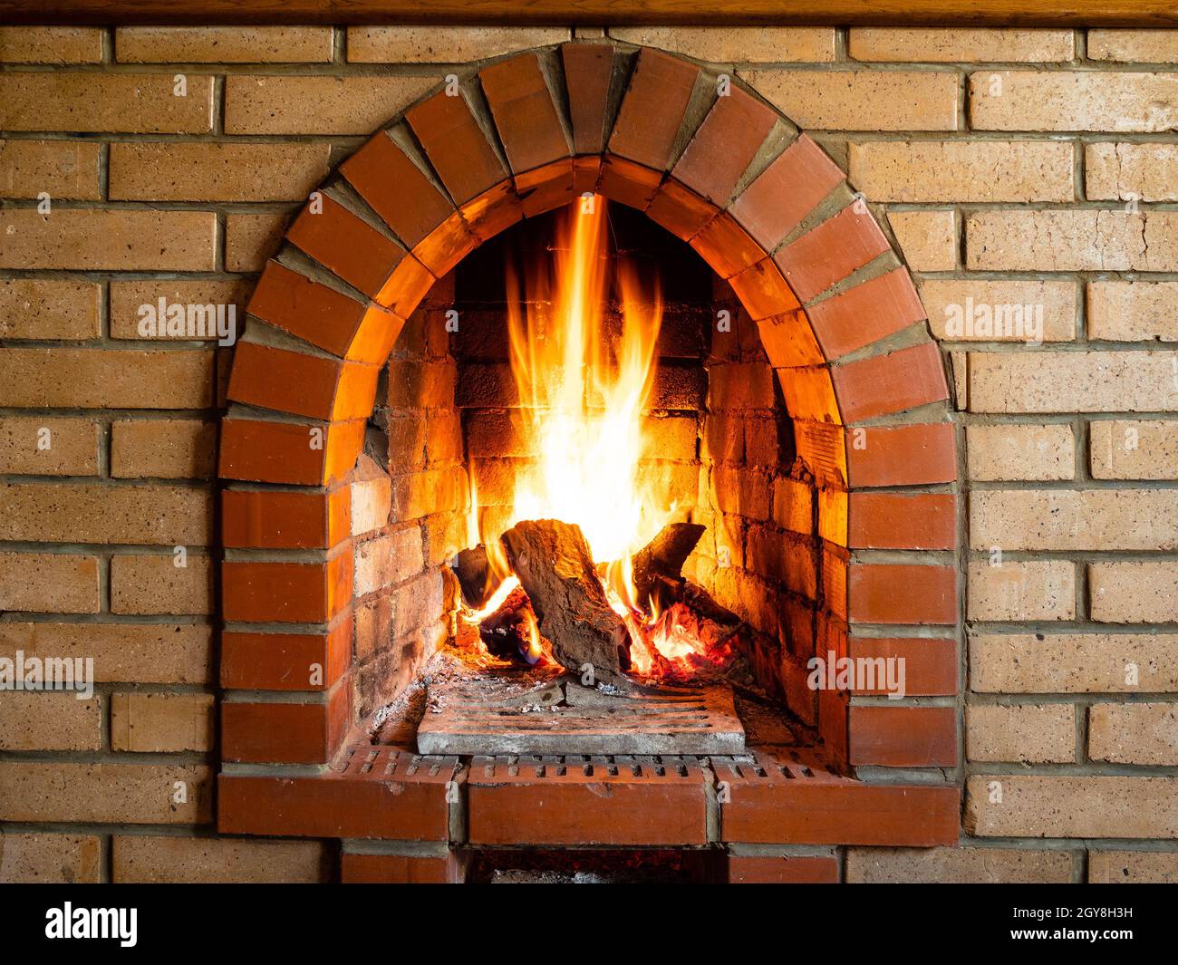 vue de face d'un foyer en briques avec bois en feu dans la maison de campagne Banque D'Images