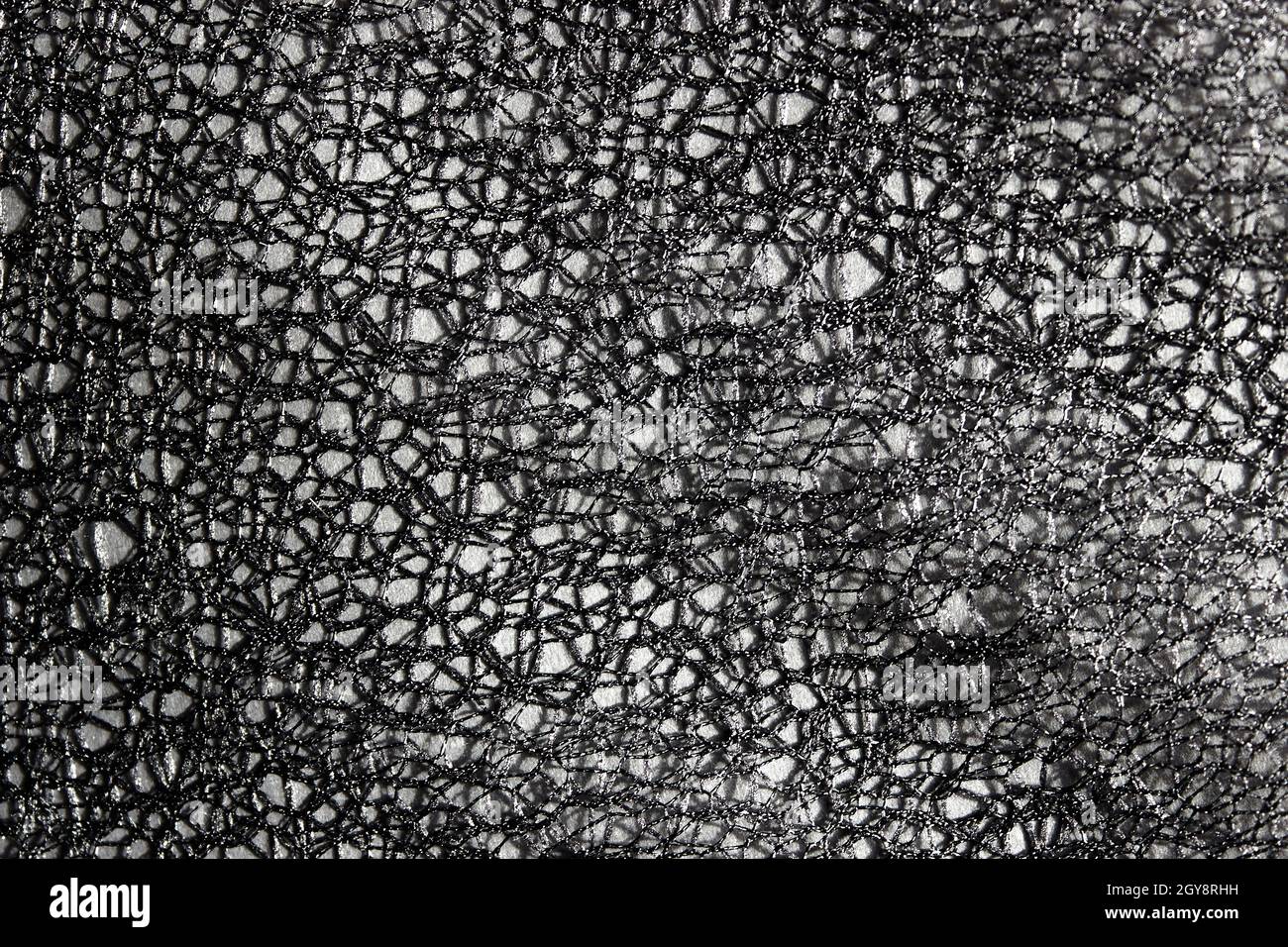 Fond abstrait en dentelle gris foncé.Arrière-plan sombre pour le design, les réseaux sociaux, le texte.Arrière-plan ajouré, mesh, tissu. Banque D'Images