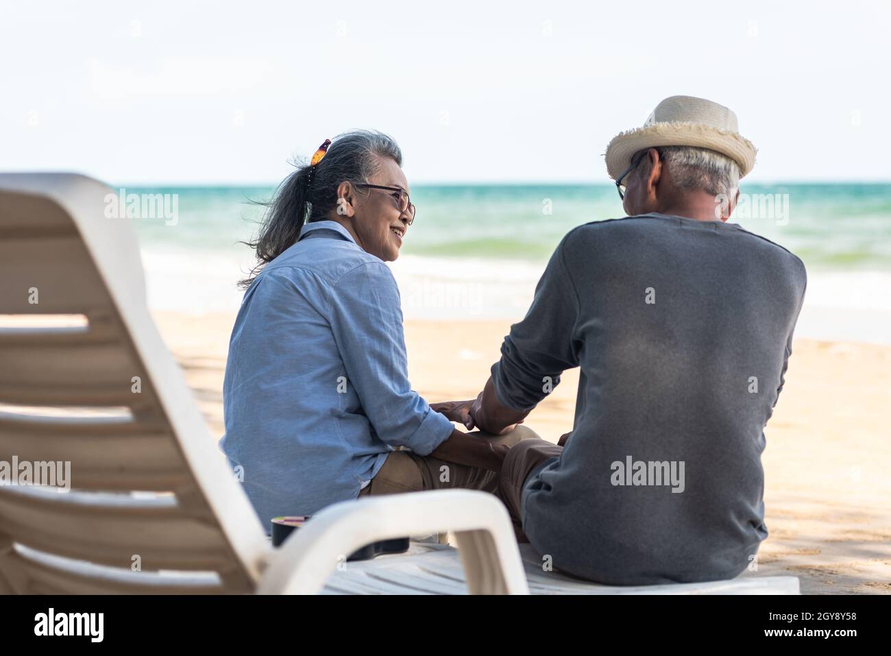 Famille asiatique heureuse, couple senior assis sur des chaises avec dos sur la plage vacances de voyage parler ensemble, romantique personnes âgées profiter Voyage vacances d'été Banque D'Images