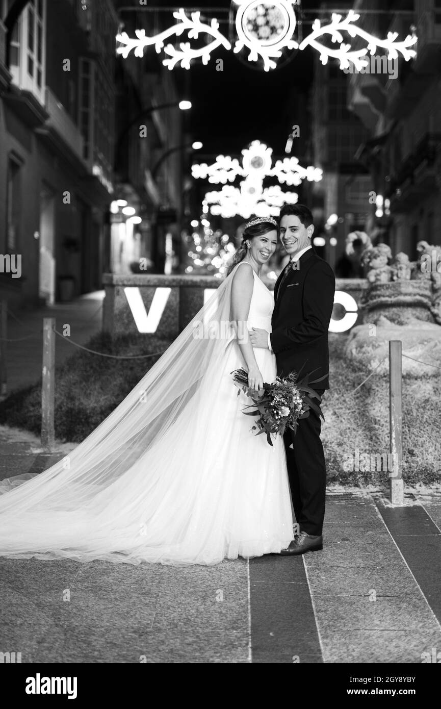 Couple sur leurs vêtements de mariage contre la décoration de rue de noël la nuit Banque D'Images