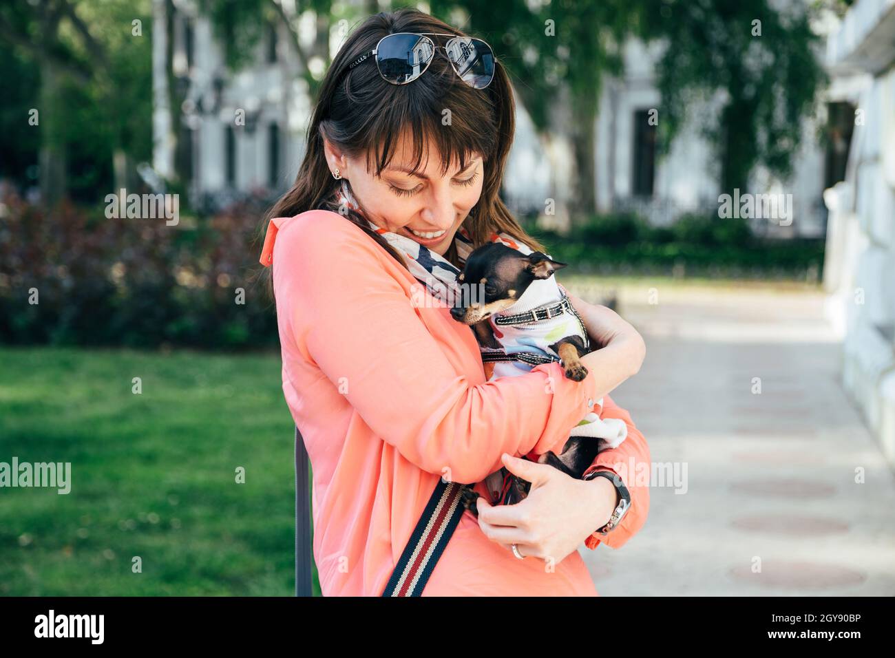 Bonne jeune femme caucasienne embrassant son petit chien, le russe Toy Terrier ou le russe Toy Terrier, vêtu d'un costume d'automne.Animaux de compagnie adorés Banque D'Images