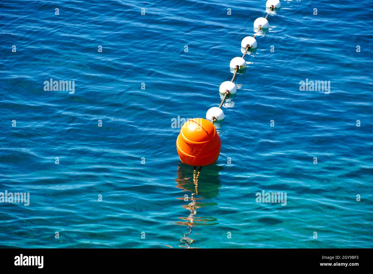 Bouée flottante en plastique rouge sur la surface bleue et turquoise de la mer Banque D'Images
