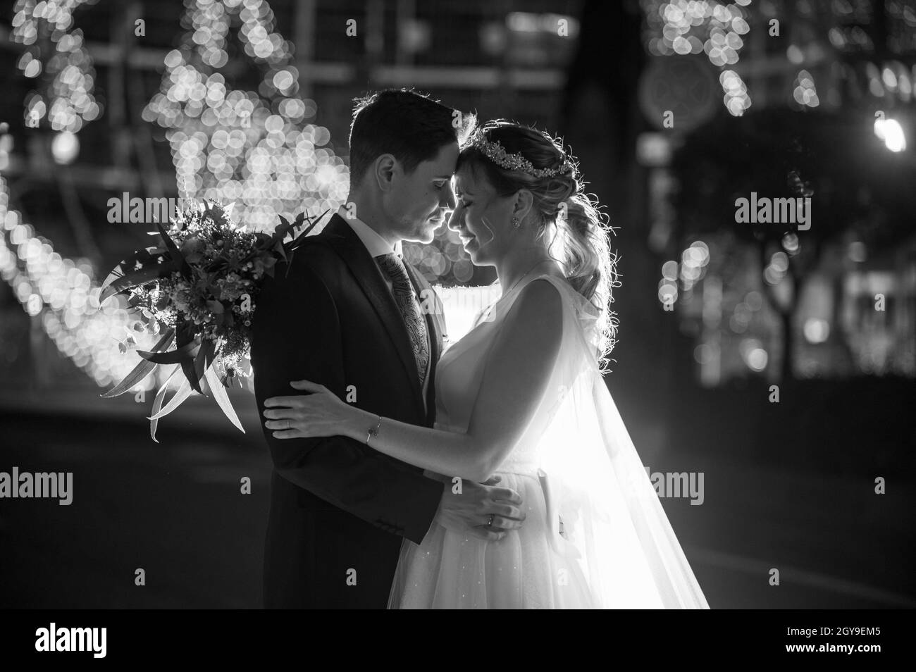 Couple sur leurs vêtements de mariage contre la décoration de rue de noël la nuit Banque D'Images
