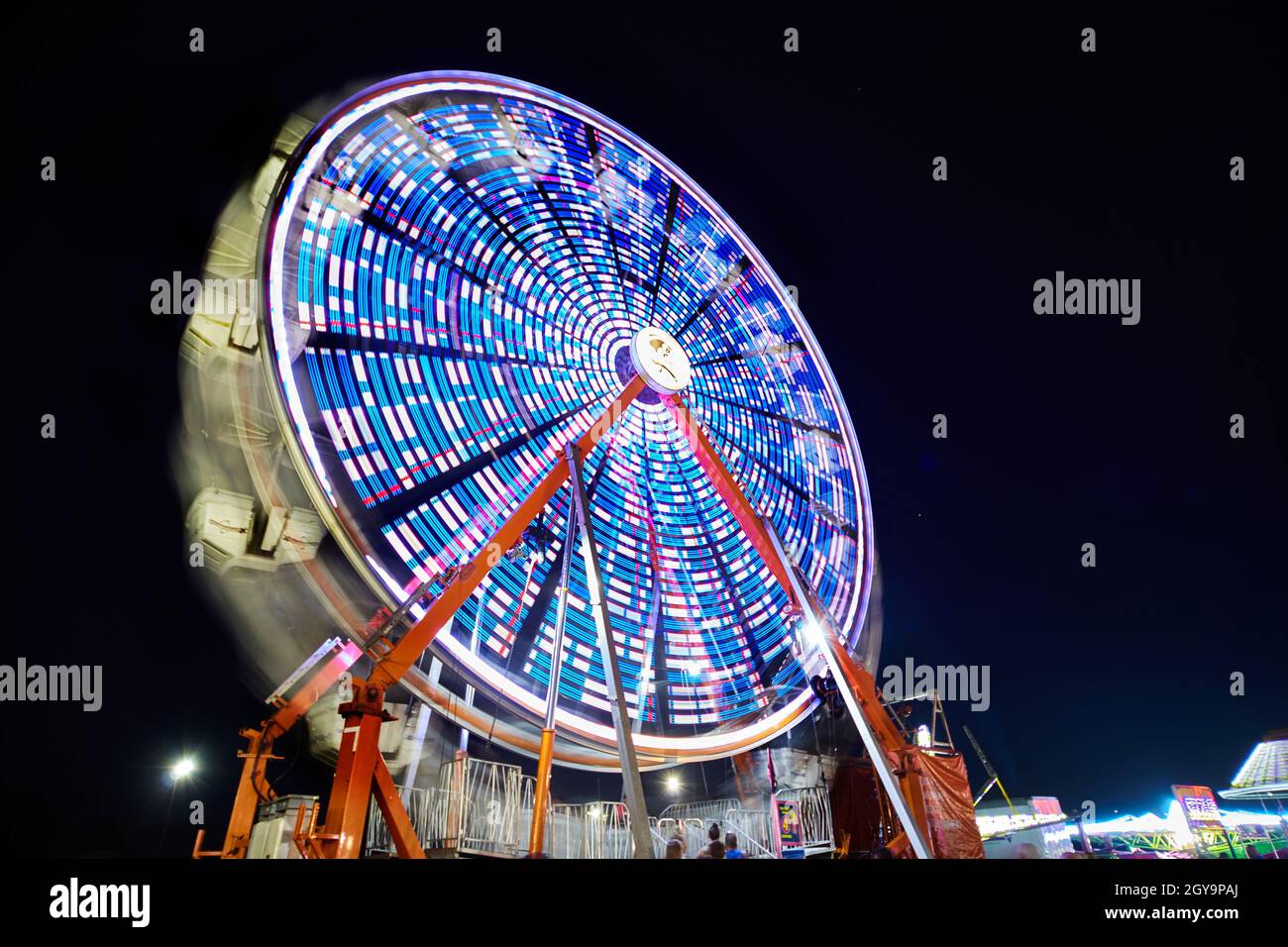 Grande roue la nuit avec lumières bleues et blanches à une foire ou un carnaval Banque D'Images