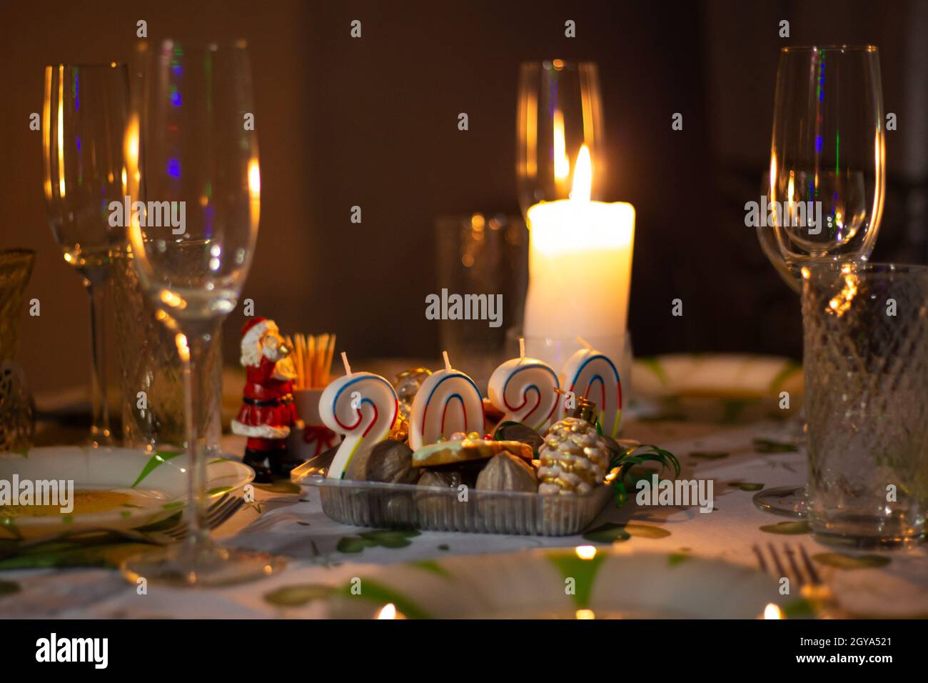 Table de Noël avec ustensiles et verres, table avec bougies allumées, dans une pièce sombre Banque D'Images