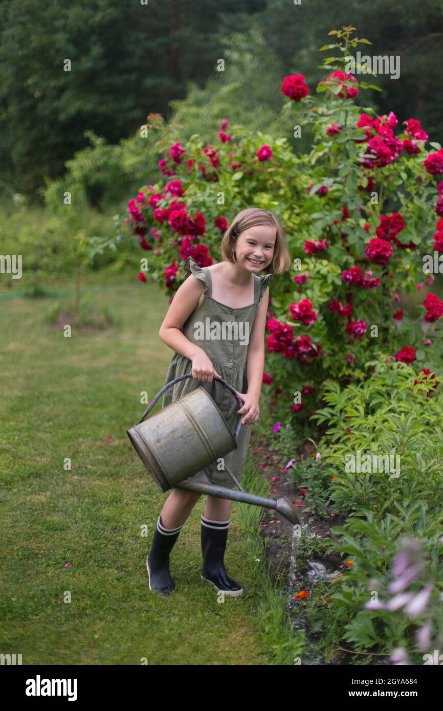 Une fille arrosoir des fleurs dans le jardin. Banque D'Images
