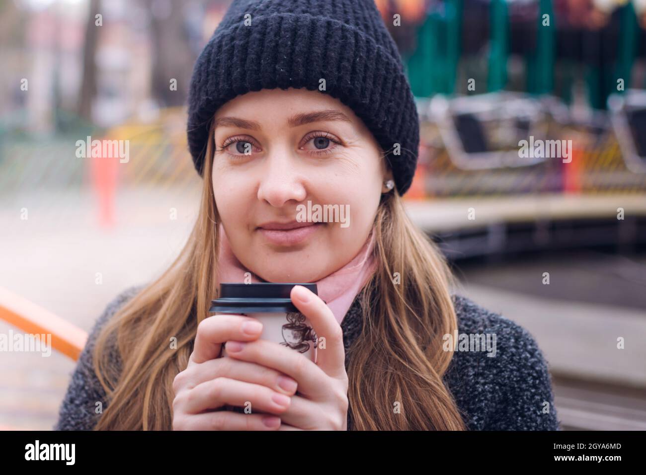 Une fille souriante tient une boisson chaude à l'extérieur par temps froid Banque D'Images