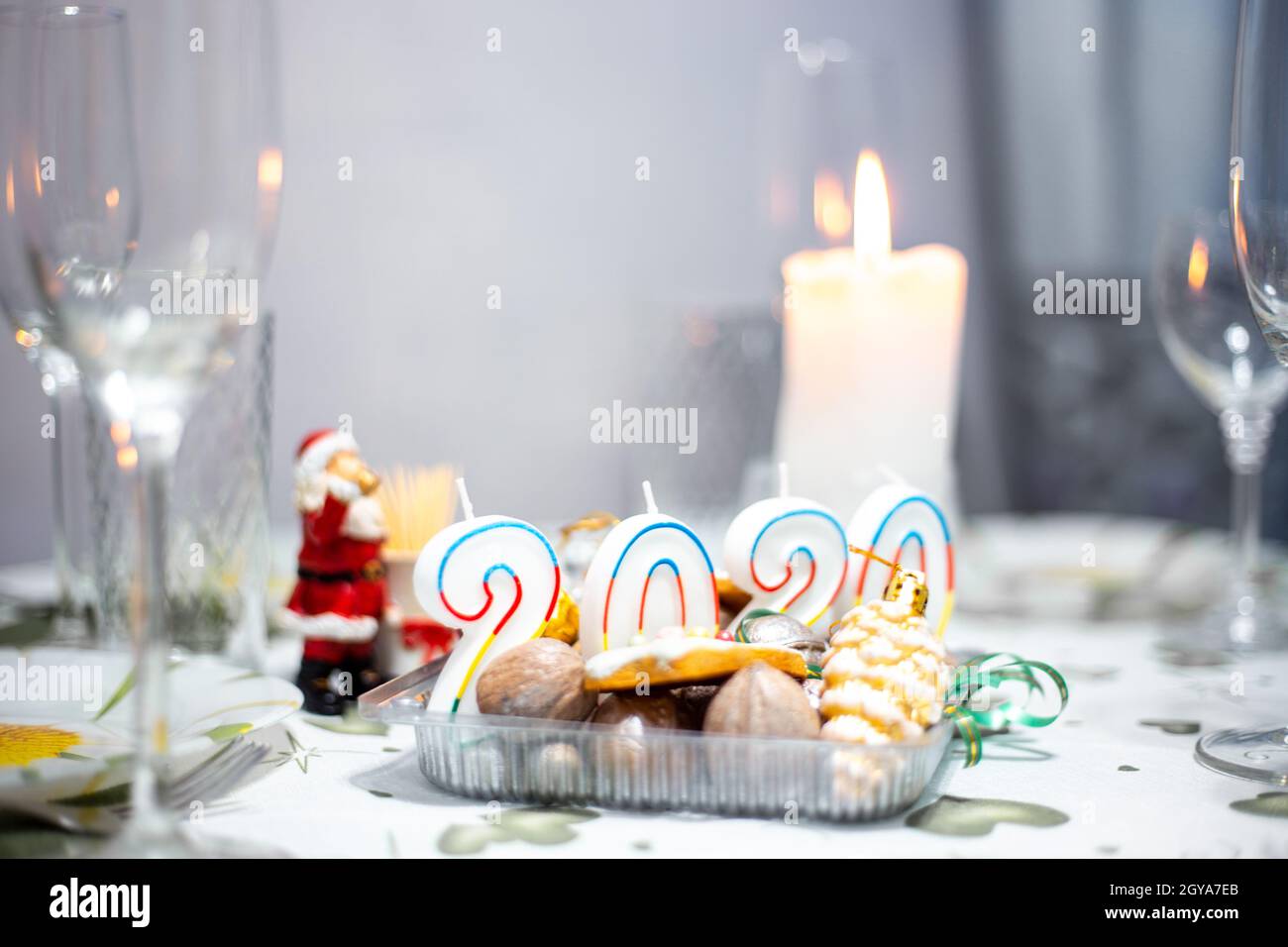 Table de Noël avec ustensiles et verres, table avec bougies allumées, dans une pièce sombre Banque D'Images