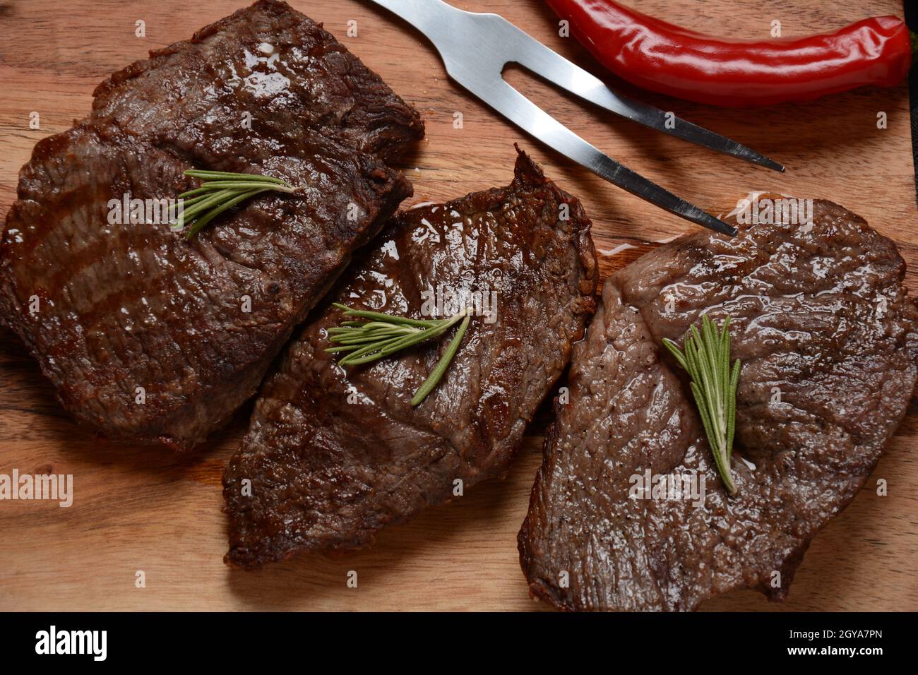 Steak de bœuf grillé juteux au romarin, viande frite, gros plan. Top Blade steaks sur bois Banque D'Images