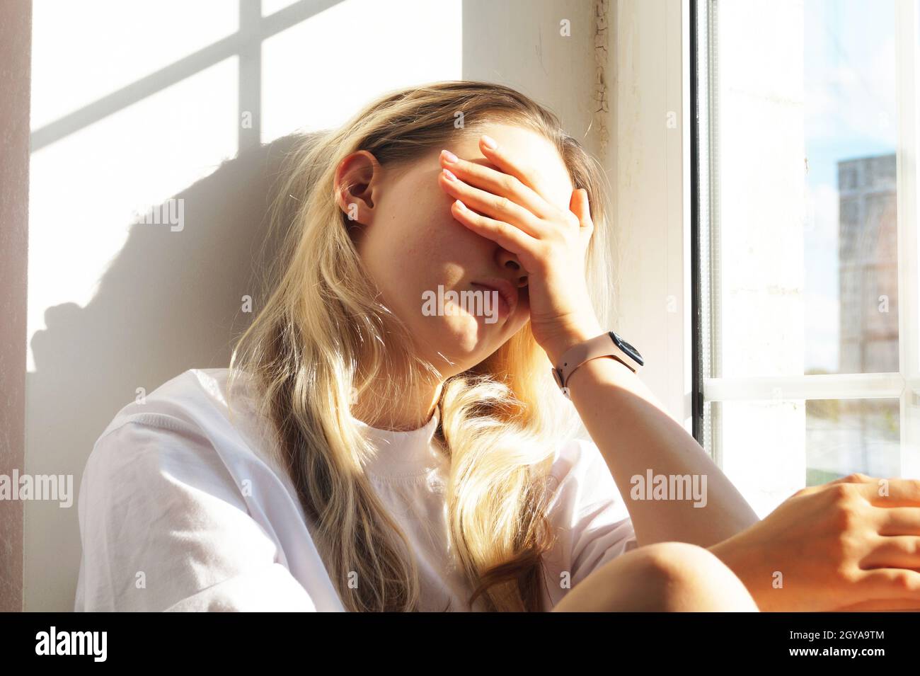 Une jeune fille triste est assise sur le rebord de la fenêtre Banque D'Images
