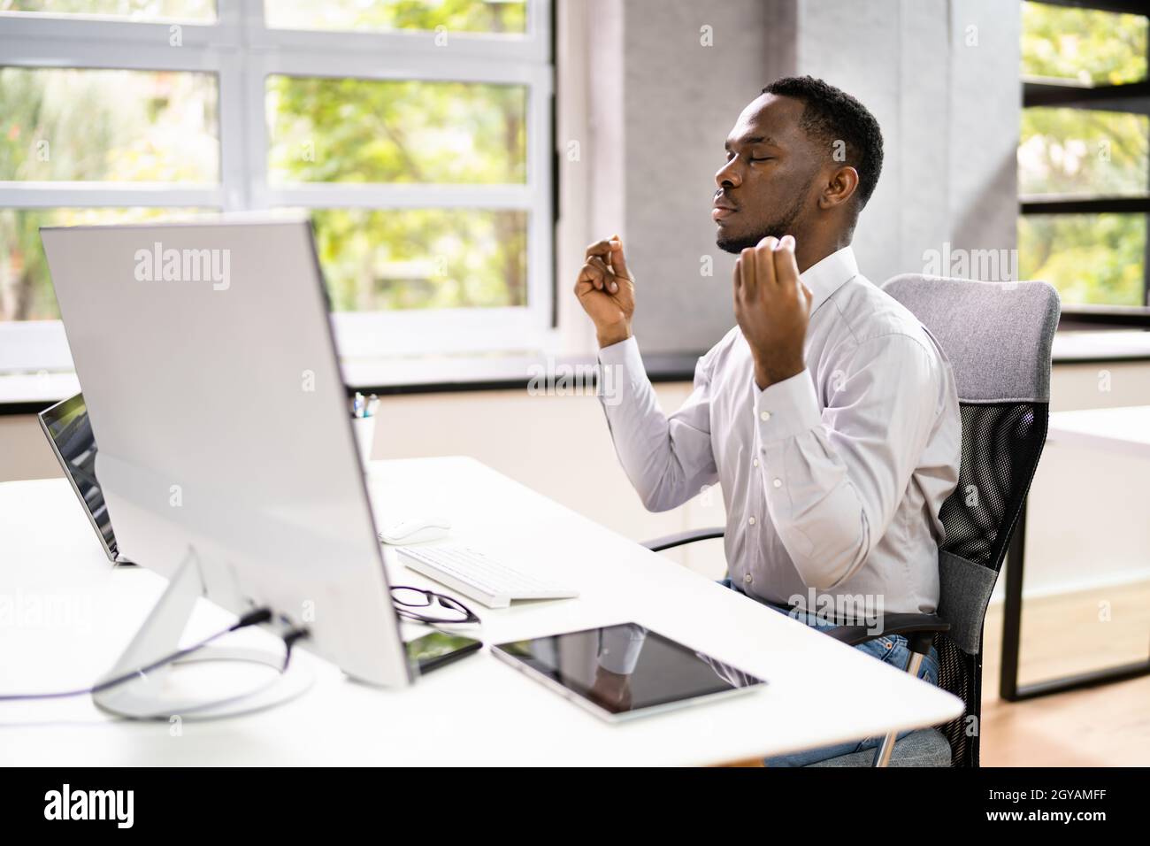 Méditation d'homme afro-américain derrière l'ordinateur au bureau Banque D'Images